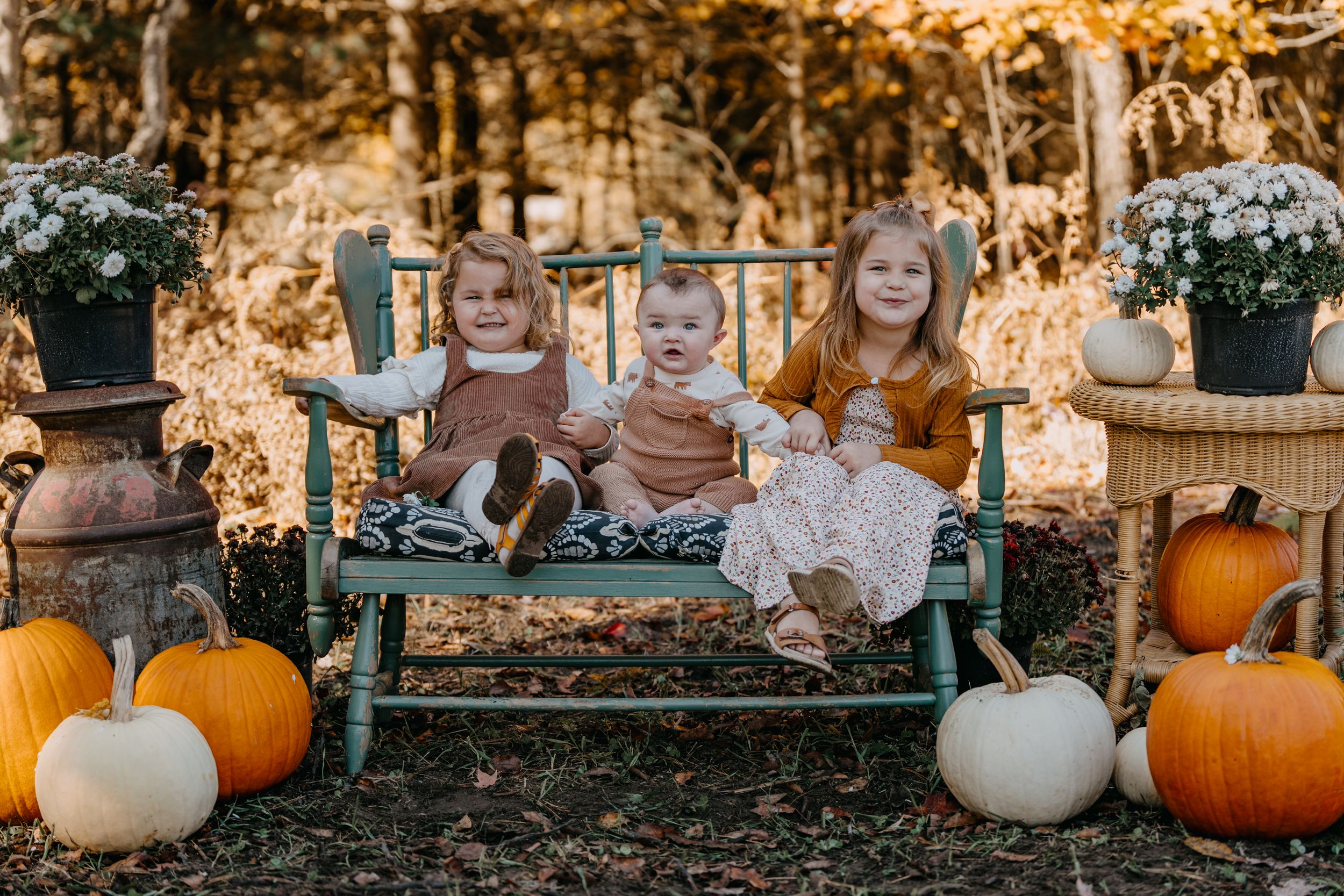 Seasonal fall outdoor scene with vintage bench, pumpkins and white gourds arranged with rustic decor elements.