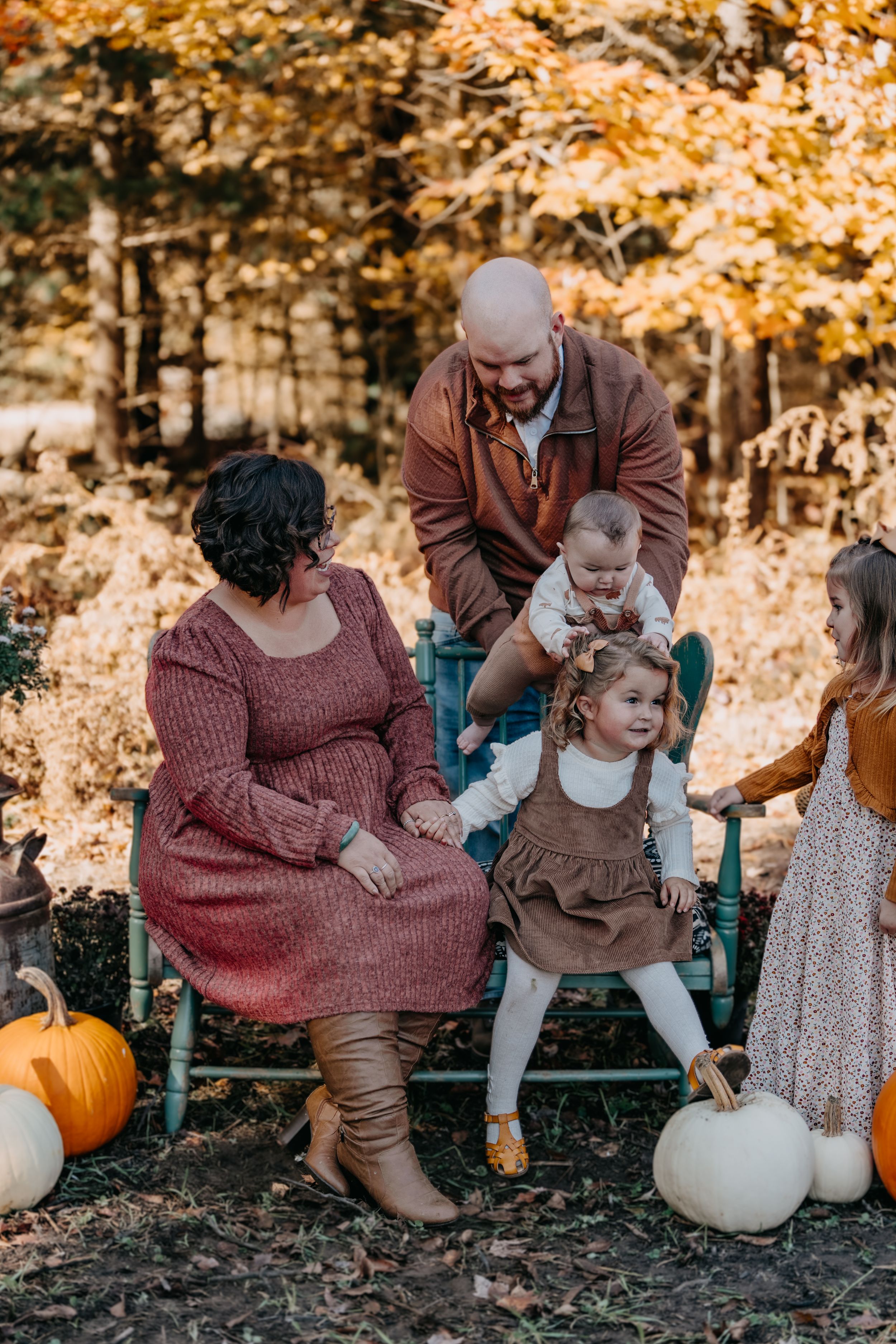 A heartwarming autumn family photoshoot with pumpkins and falling leaves in warm golden lighting.