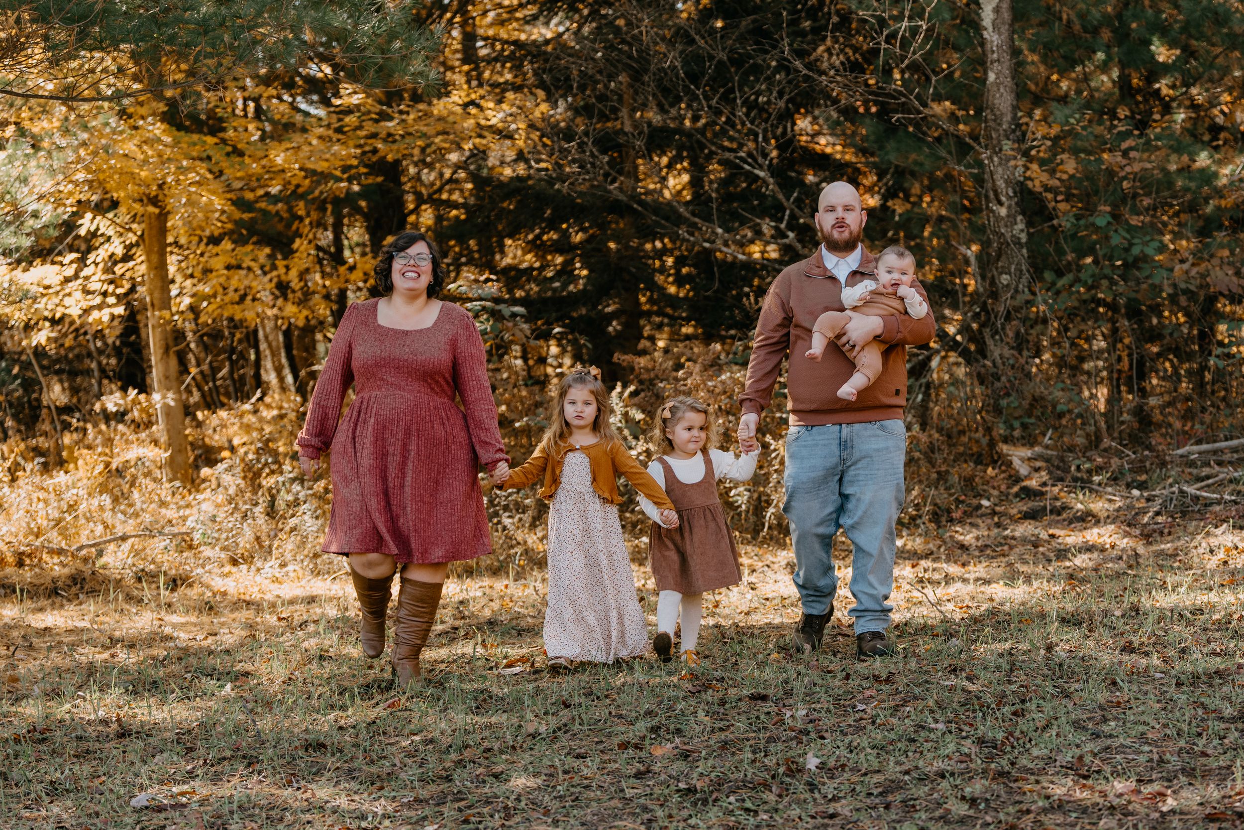 A group walks through autumn woods together on a sunny afternoon amidst golden fall foliage.