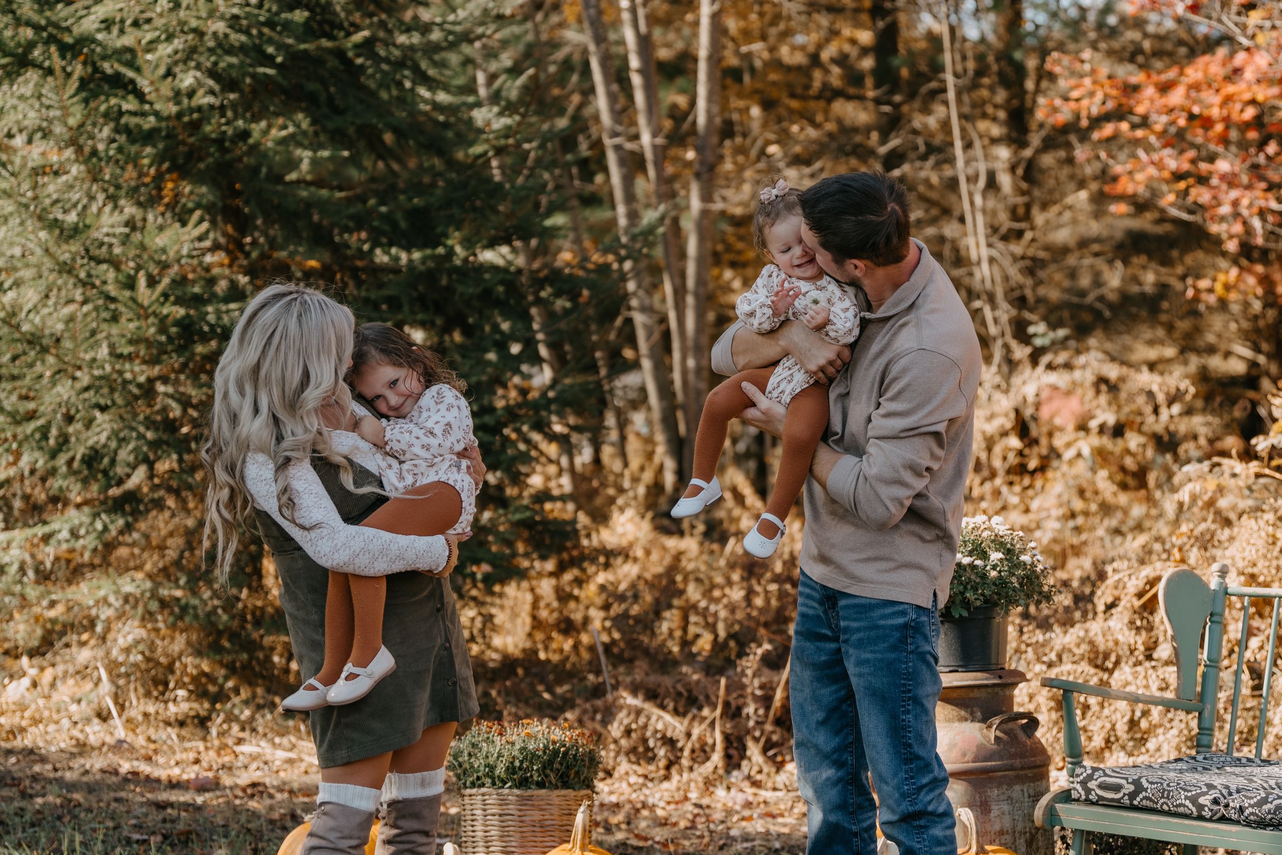 A family spending time together outdoors in autumn, surrounded by fall foliage and woodland scenery.