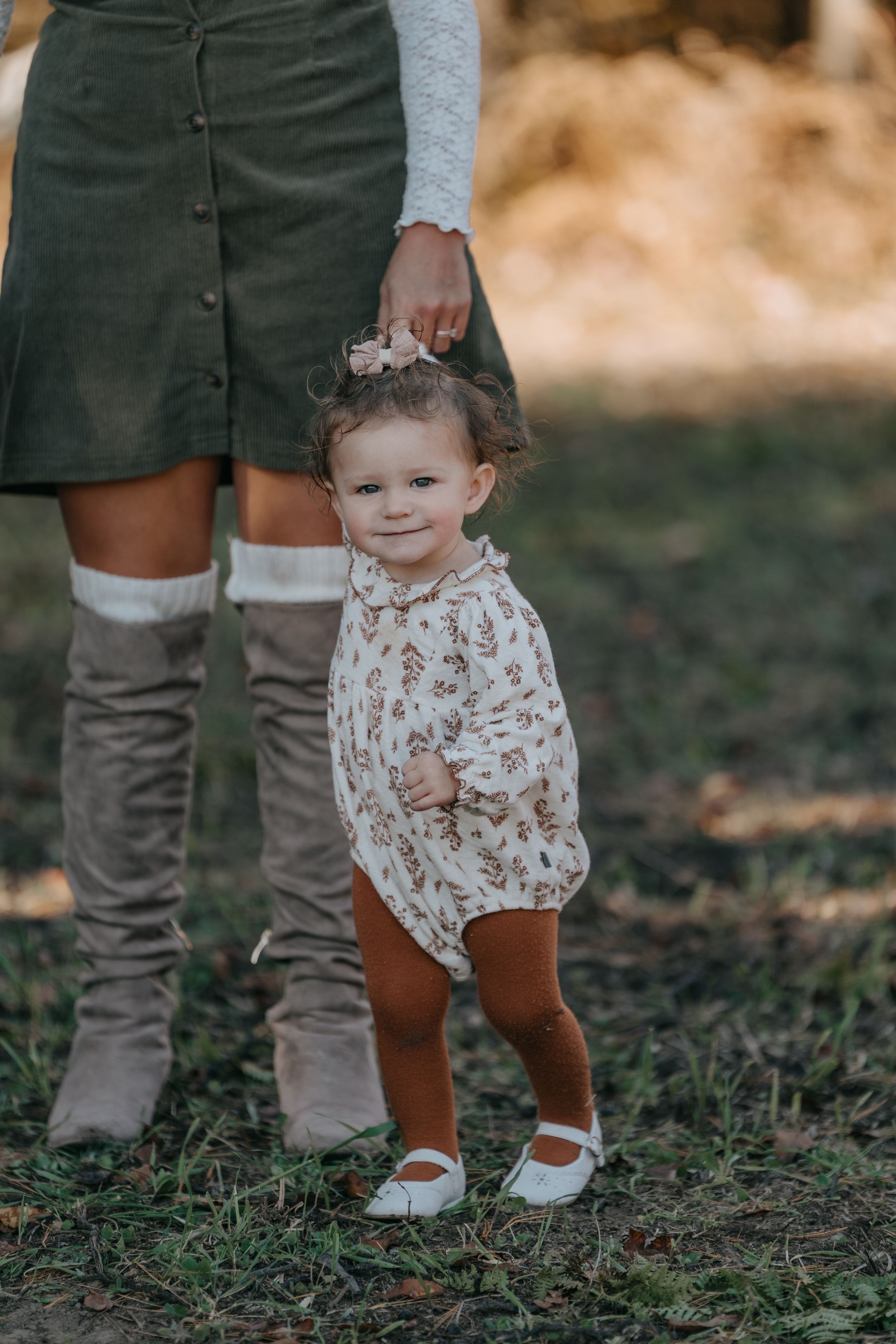 Close-up sequence of small boots and floral dress against grass in autumn setting.