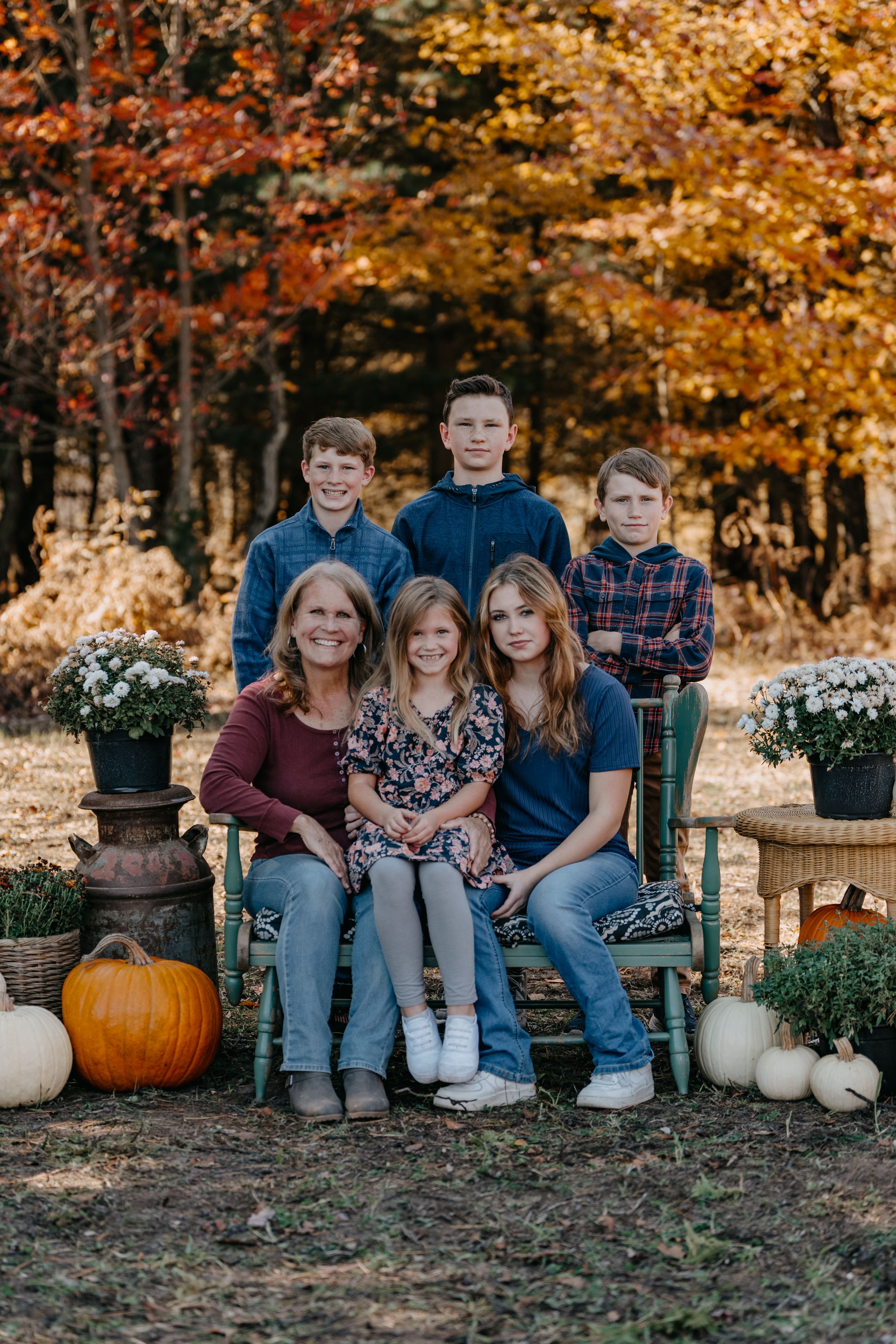 Group portrait in autumn setting with white pumpkins and fall foliage displaying warm orange and yellow colors.