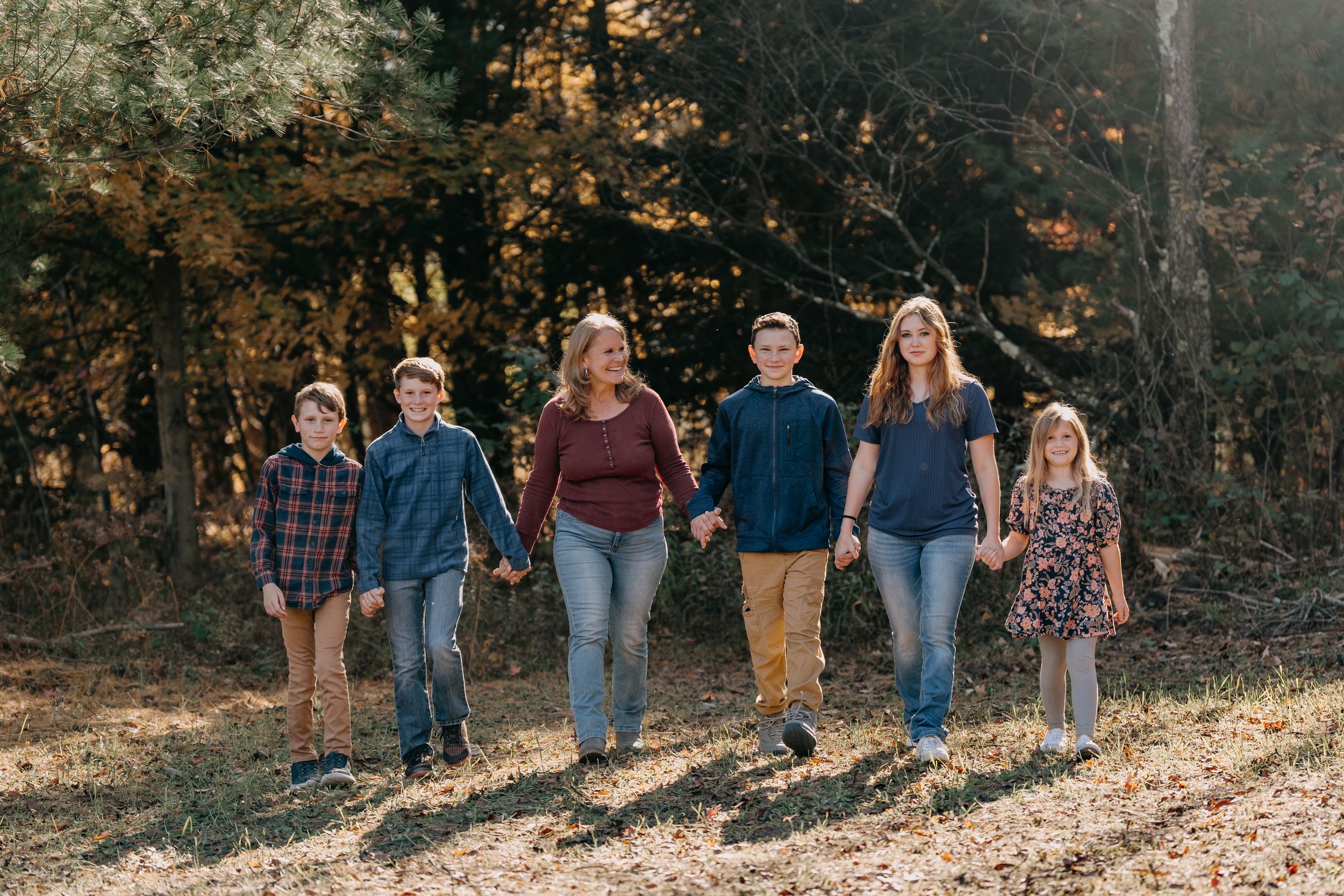 Group walking together on path with autumn foliage and golden sunlight filtering through trees.