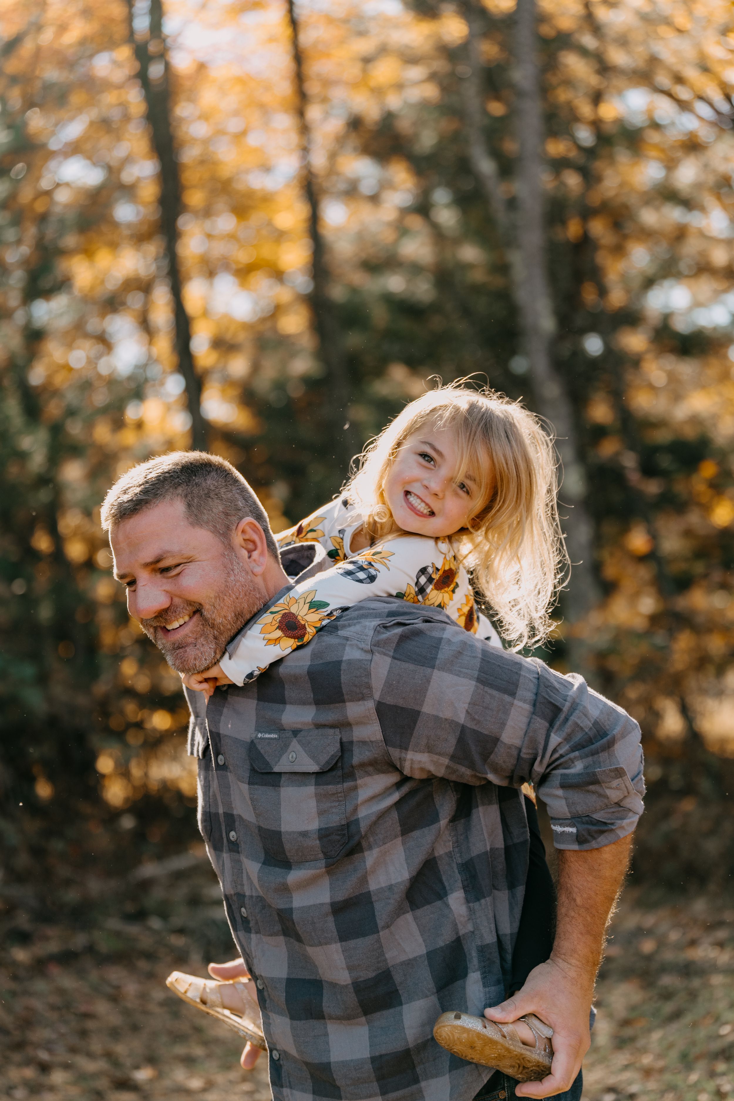A playful piggyback ride scene in an autumn forest with golden foliage in the background.