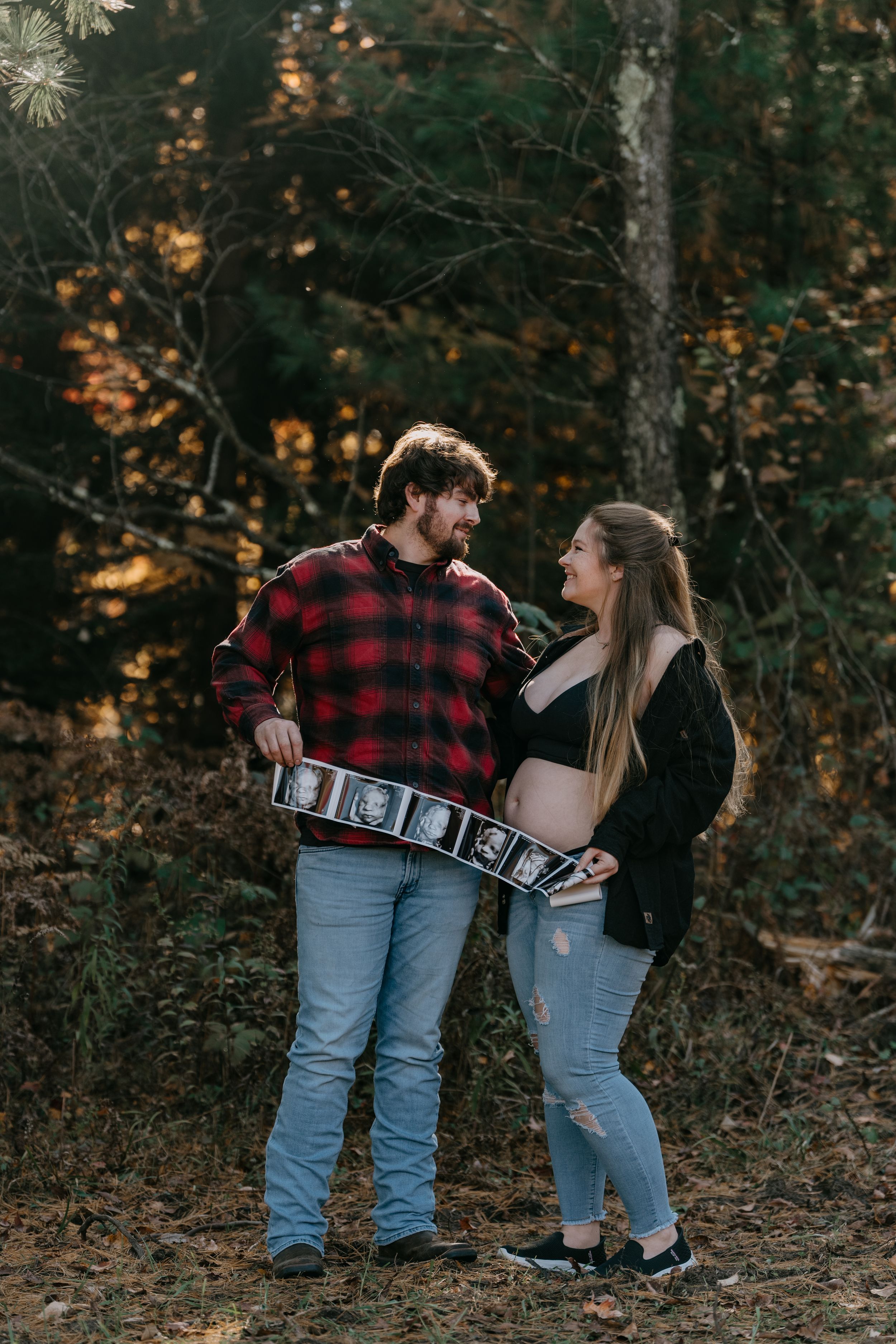 A couple shares a romantic moment in the woods holding number blocks during an autumn photo session.