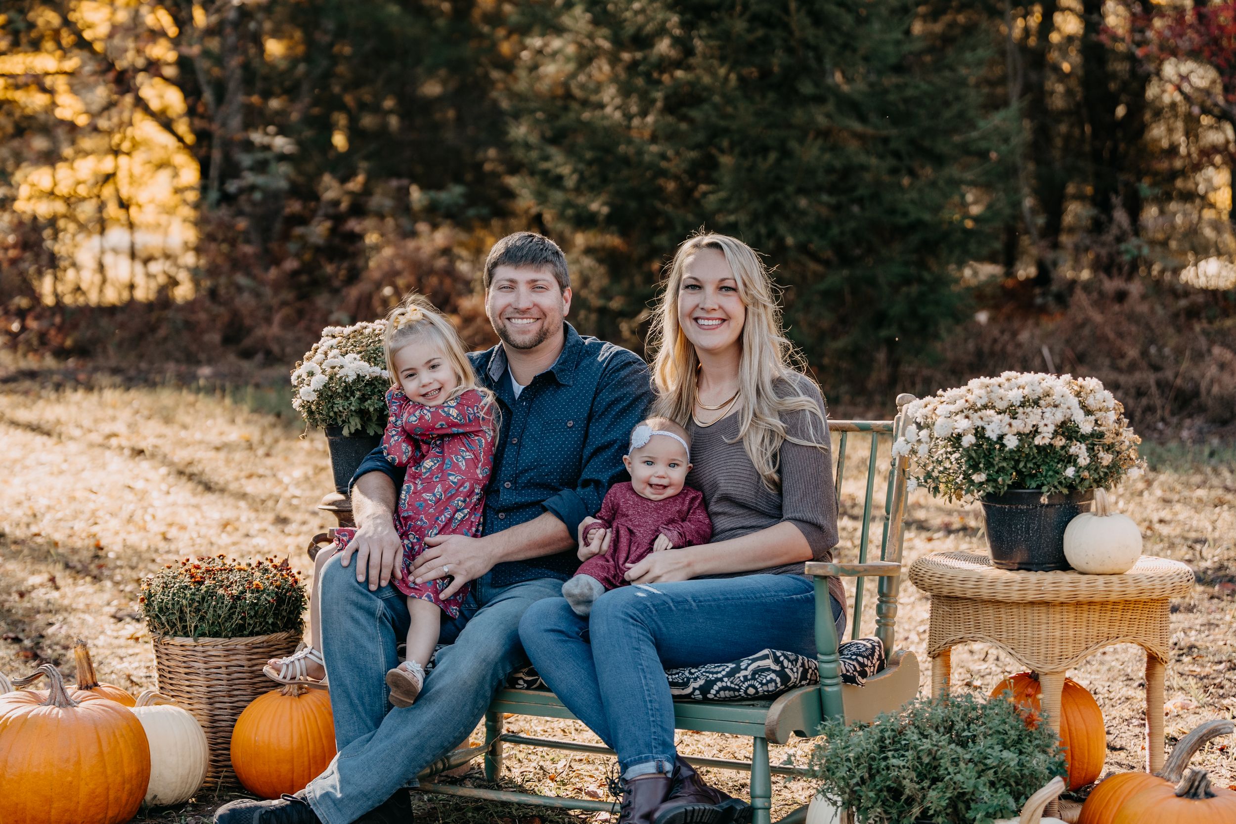 A cozy autumn outdoor photo session with pumpkins and golden leaves in the background.