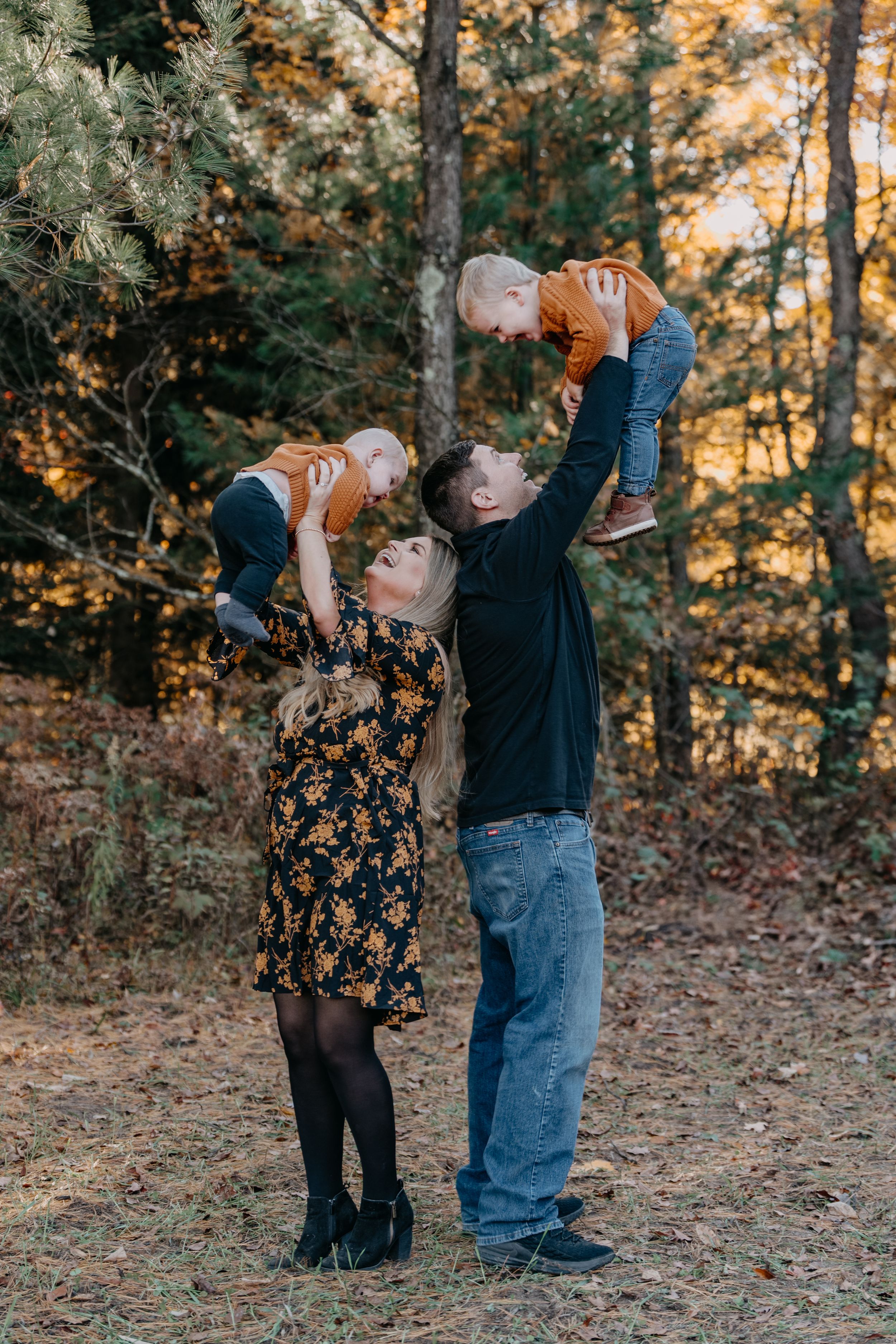 Family outdoors enjoying a fall afternoon together in a forest setting during autumn season.