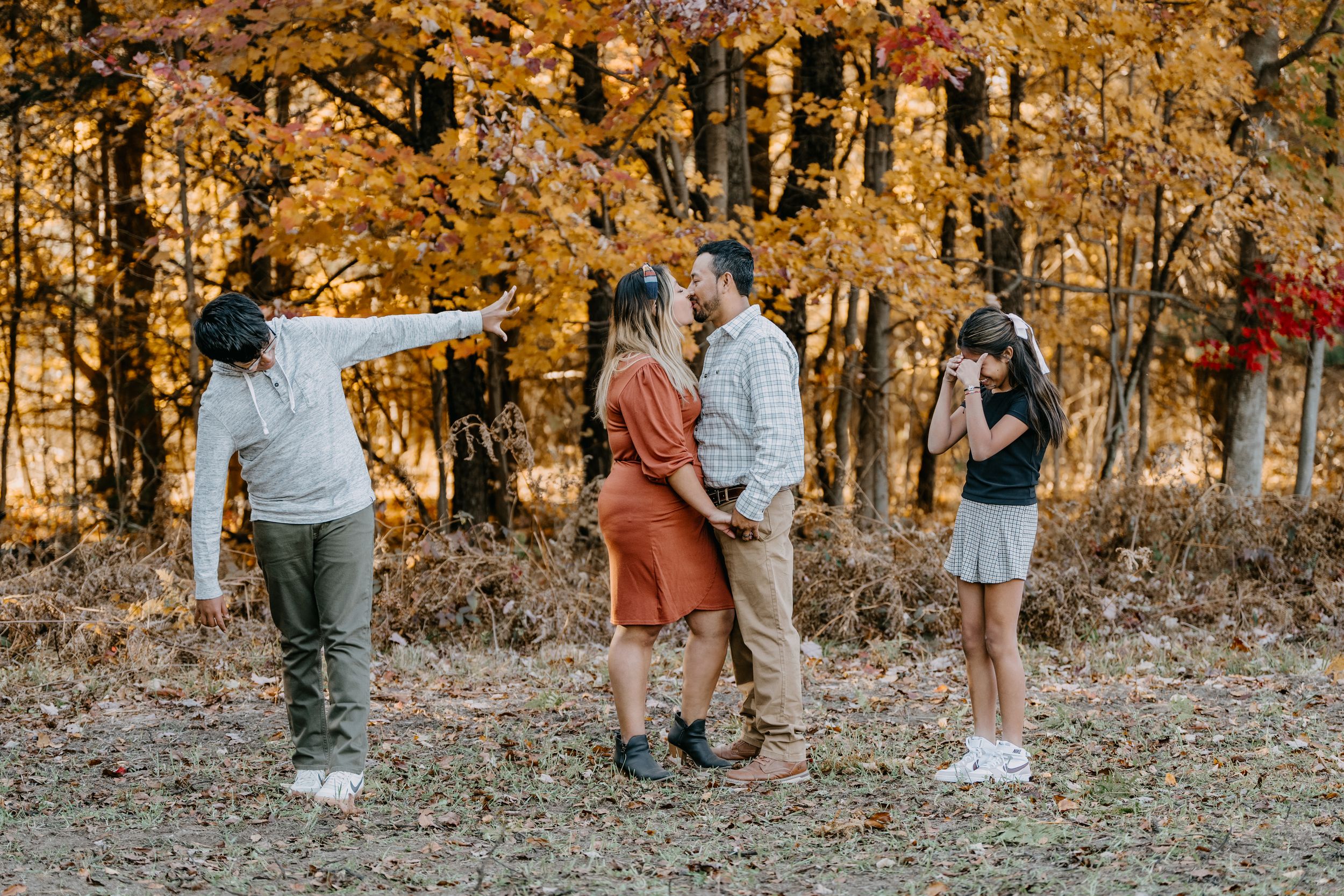Group of people enjoying an autumn day in the woods with golden foliage in the background.