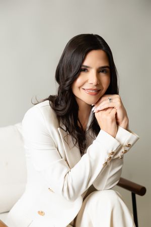 Professional studio portrait of someone in a white blazer smiling and posing in different positions on a light background.