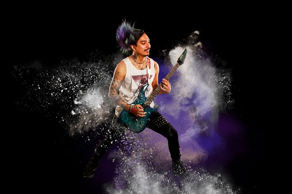 Athletic performer throws powder into the air creating colorful clouds during a dynamic dance performance on stage.