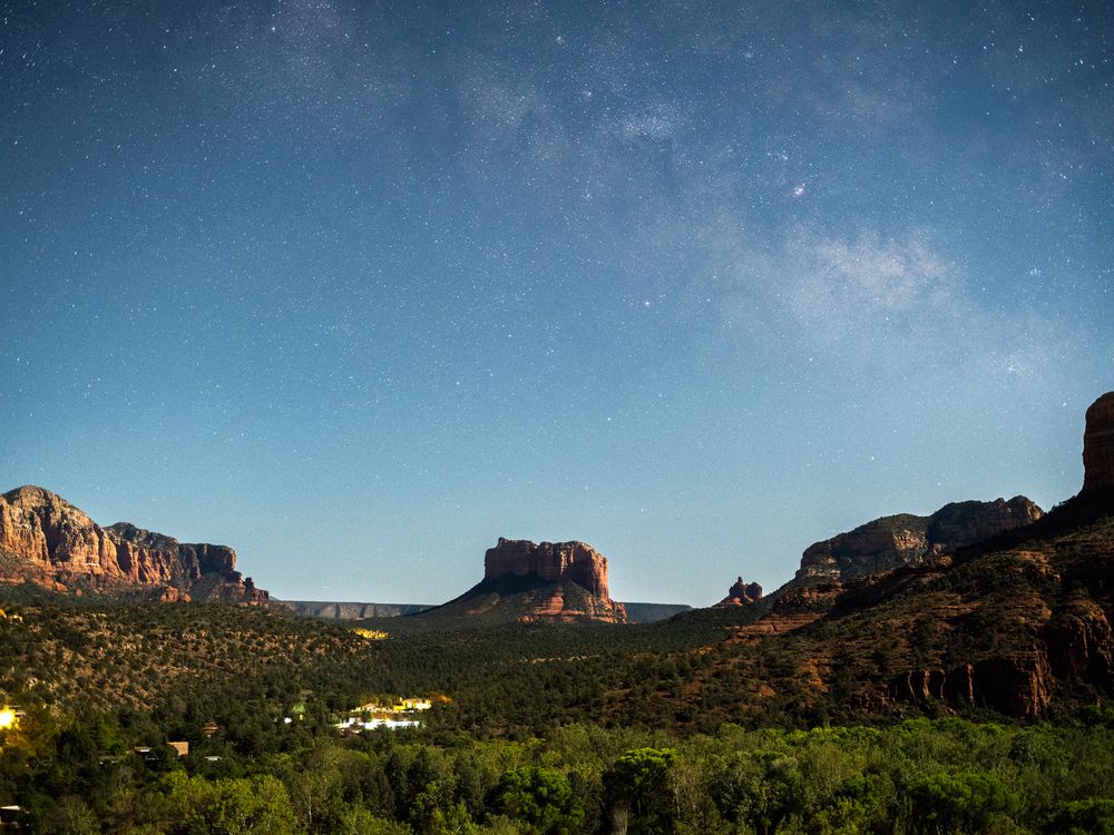 Desert mesa formations and buttes in Sedona under the night sky with a faint view of the Milky Way.