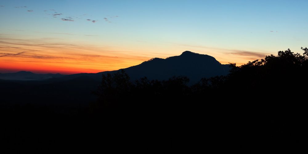 Mountain silhouettes against colorful sky during dramatic sunset with orange and purple hues.
