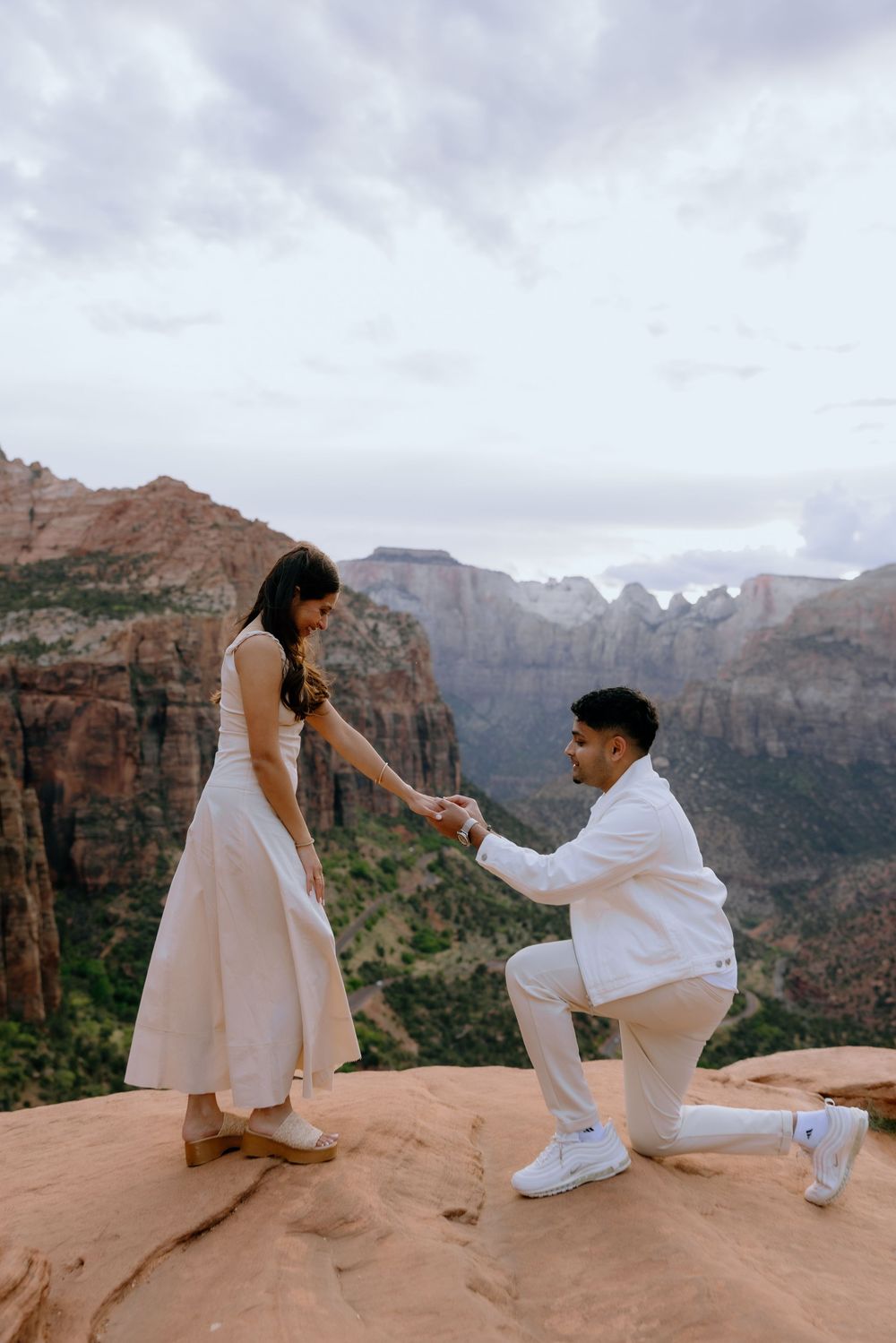 A romantic proposal moment against the scenic backdrop of red rock cliffs and mountains at Zion National Park.