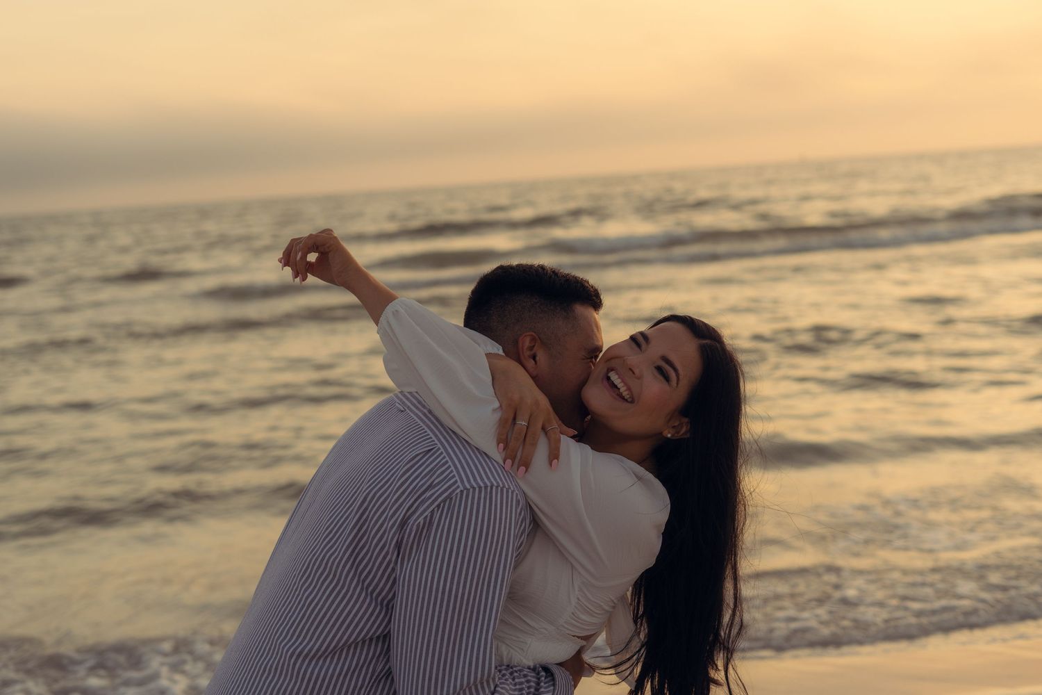 m/f couple - m is giving f a piggy back ride and he is looking over his shoulder smiling and her hair is flowing in the wind.
