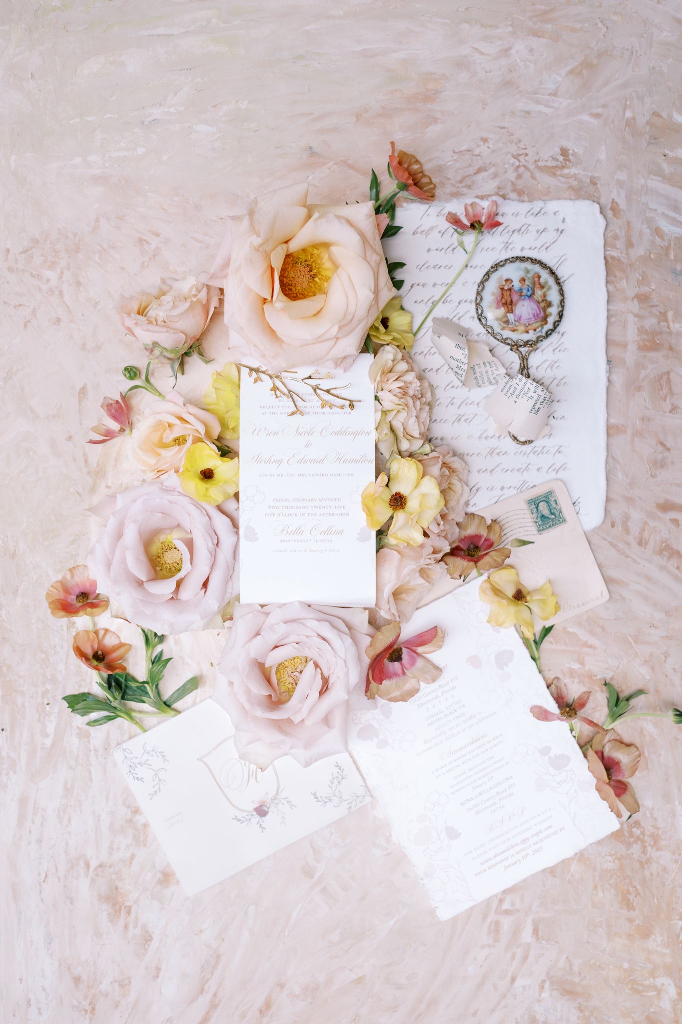 Elegant wedding invitation flatlay with blush pink roses, vintage stamps and delicate calligraphy on cream background.