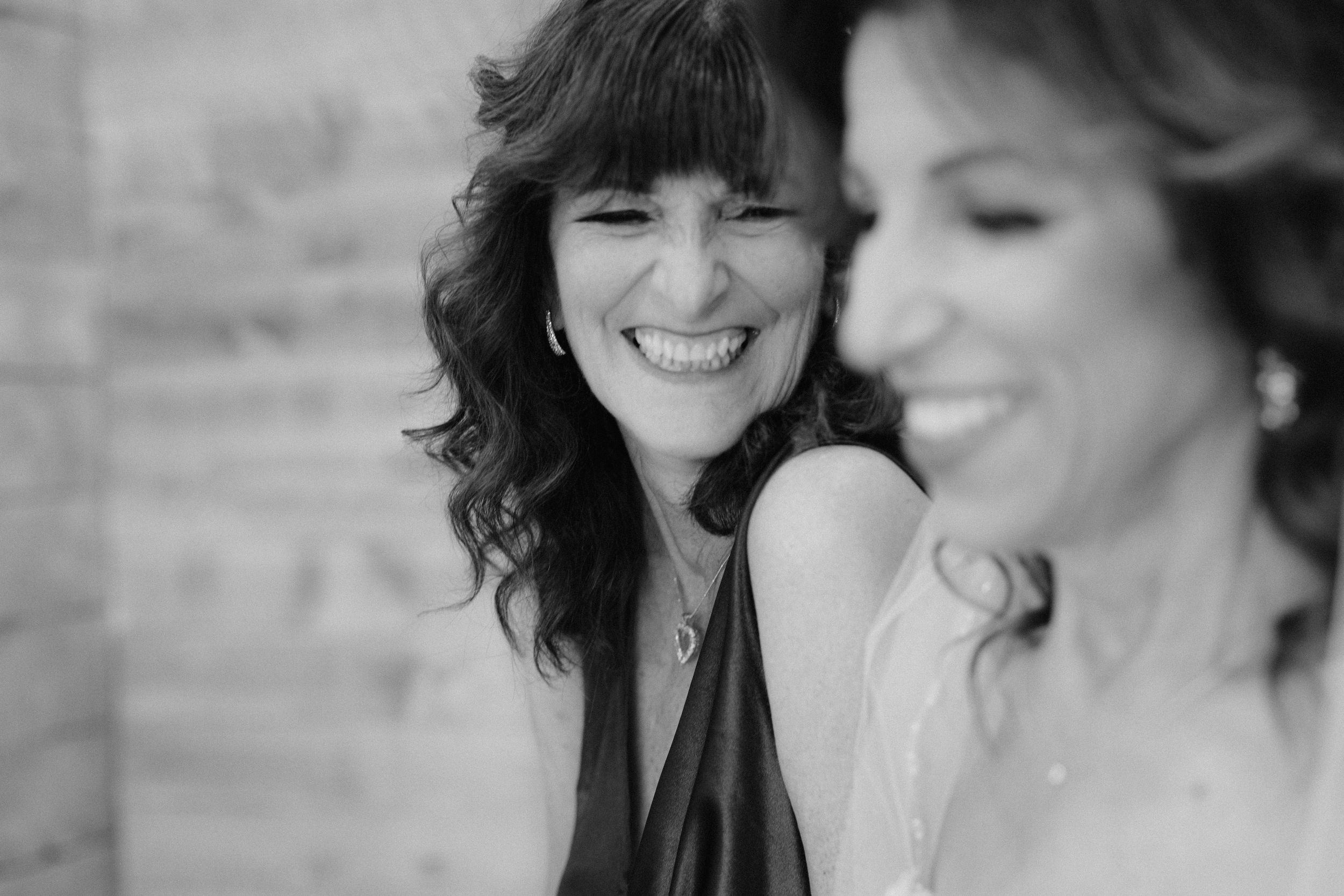 A candid black and white portrait of two women sharing a joyful laughing moment together.