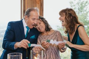 Three people laughing and enjoying themselves at an elegant dinner party with wine glasses on the table.