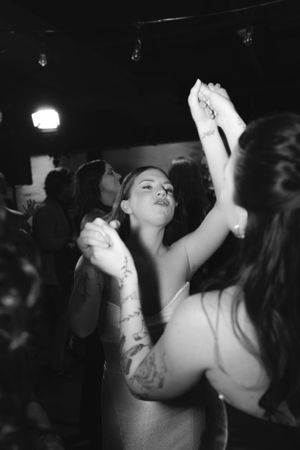 People dance energetically at a nightclub in black and white with spotlights visible in the dark background.