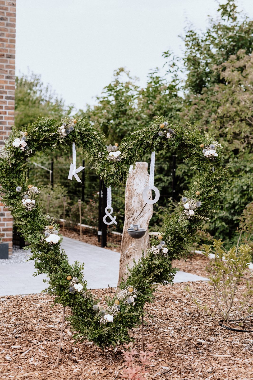 Wedding decor featuring hanging letters and floral arrangements along a garden path.
