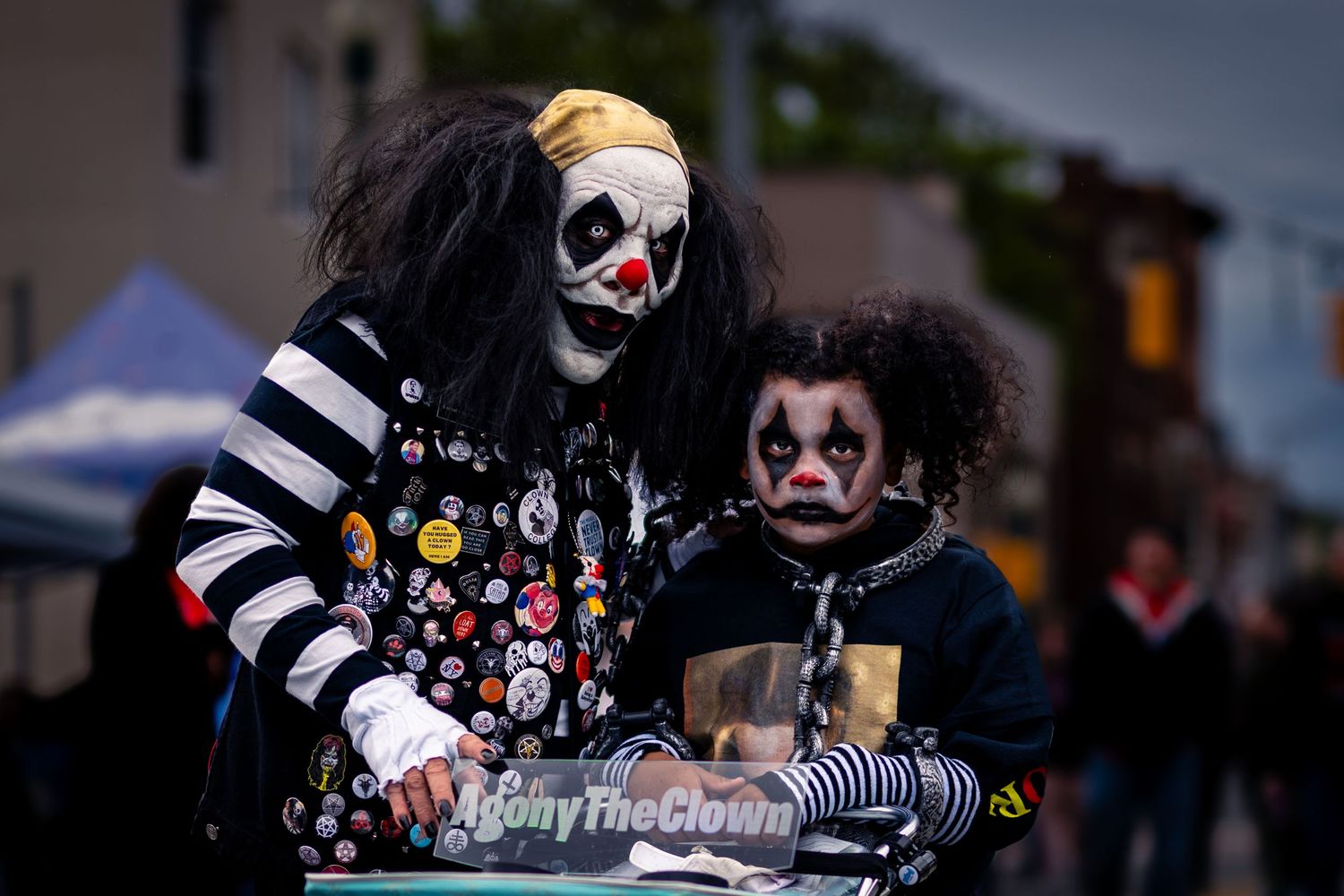 Dark-haired person in gothic clown makeup and striped clothing performs as part of a spooky circus performance.