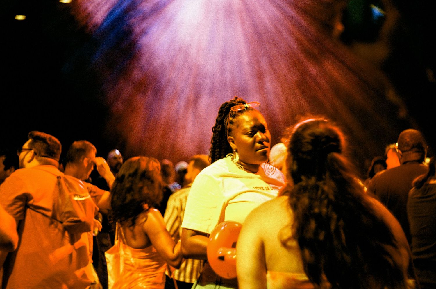 Dancers silhouetted against vibrant orange and pink stage lighting create a dynamic group performance atmosphere.