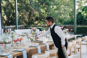 A waiter pouring water for the catering company as they prepare for the wedding