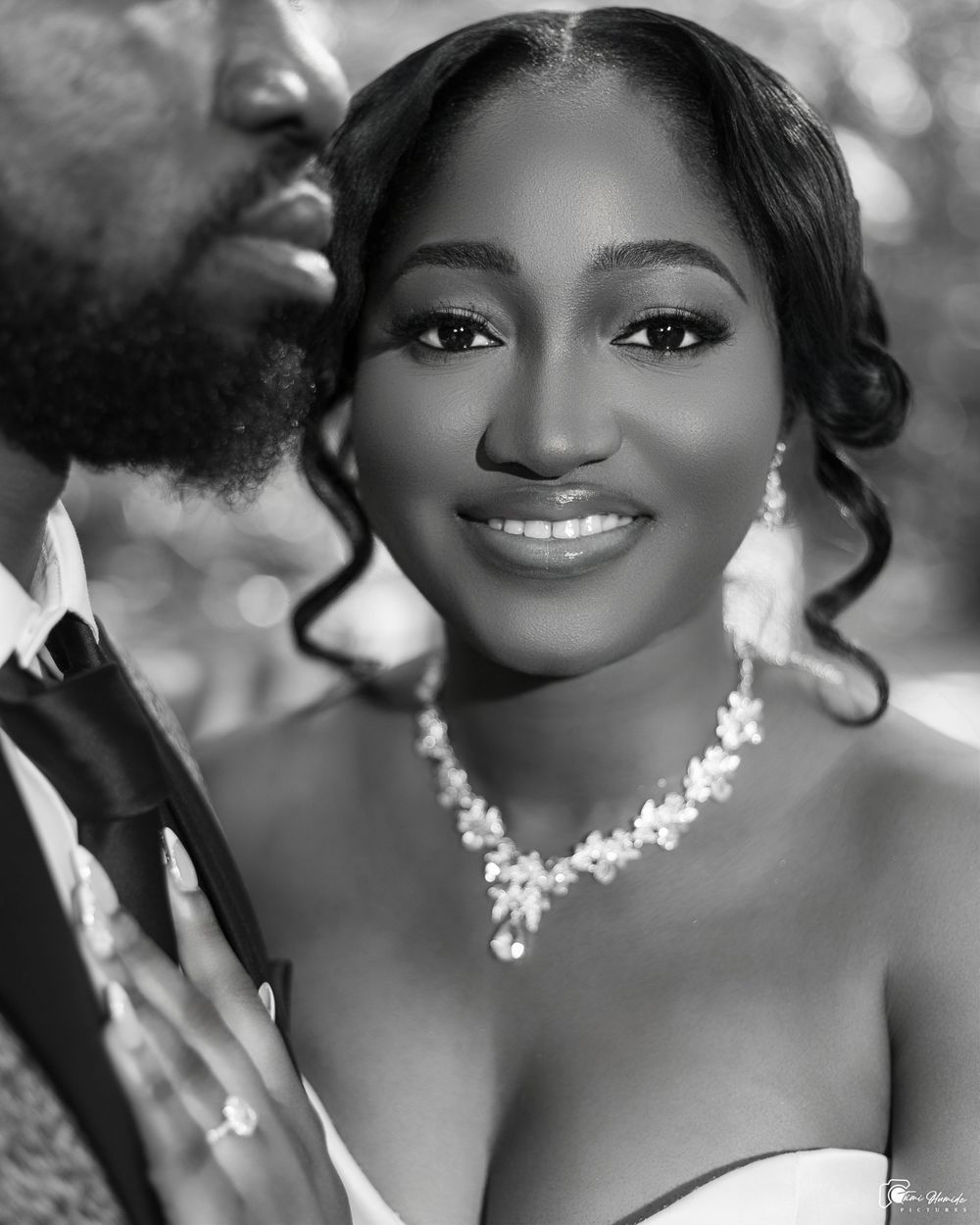 Black and white portrait of woman wearing elegant jewelry and radiant smile.