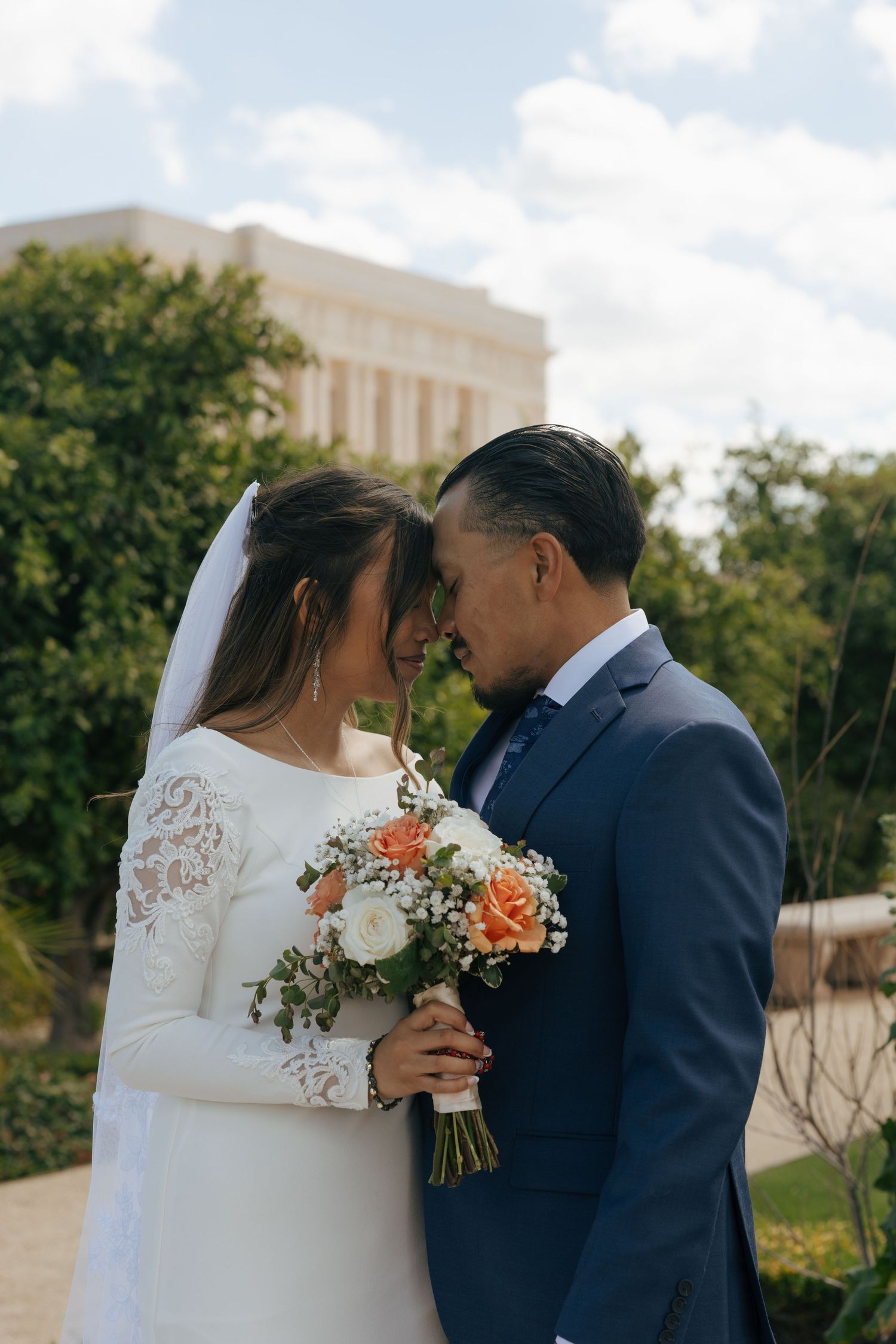 A bride and groom share an intimate moment with a bridal bouquet.