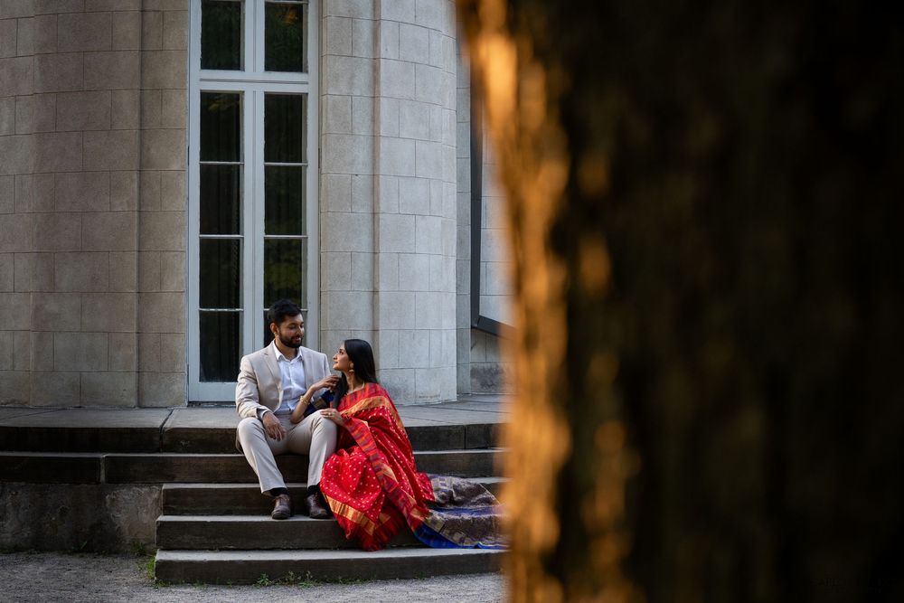 Two figures relax on stone steps of a grand building in warm evening light with columns visible.
