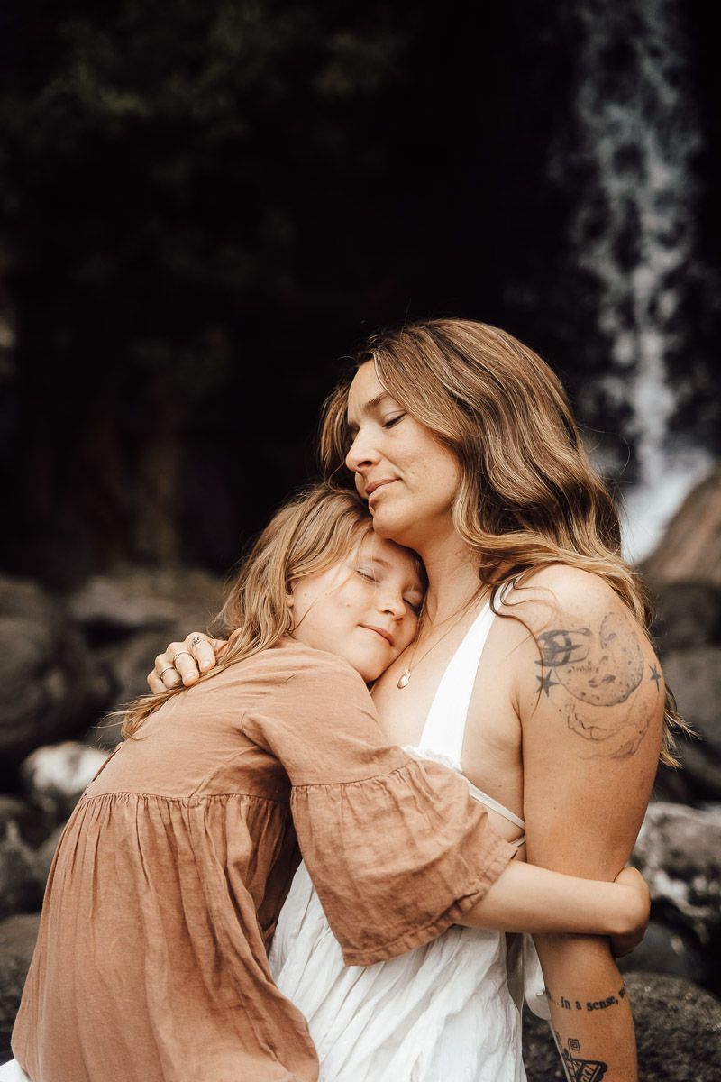 Two people in a warm natural light embrace lovingly against a dark background, capturing an intimate tender moment.