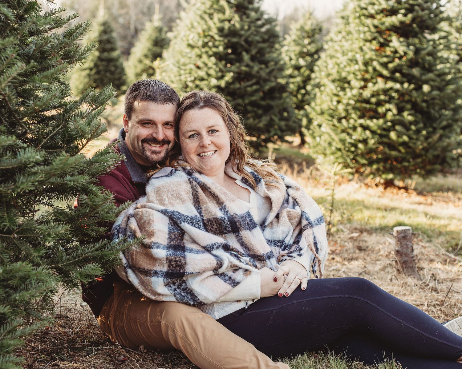 Professional photo of a couple at a tree farm wrapped in a blanket