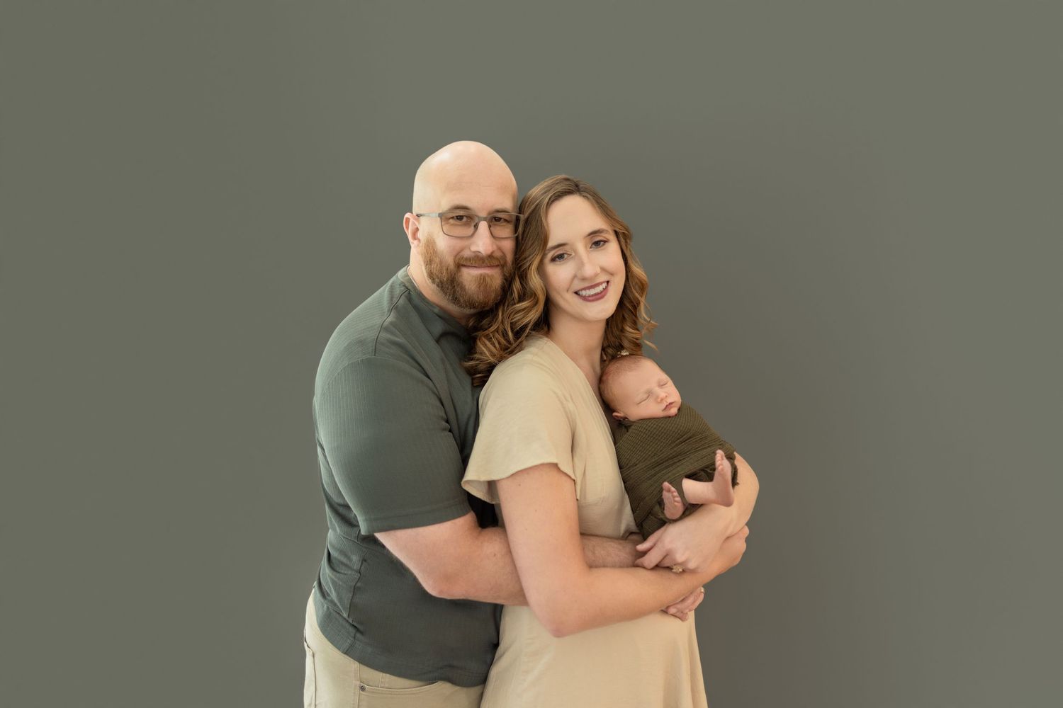 A family cuddles and embraces in an intimate portrait session against a gray background. Photos by Tampa Photographer DigitalMyst Photograph