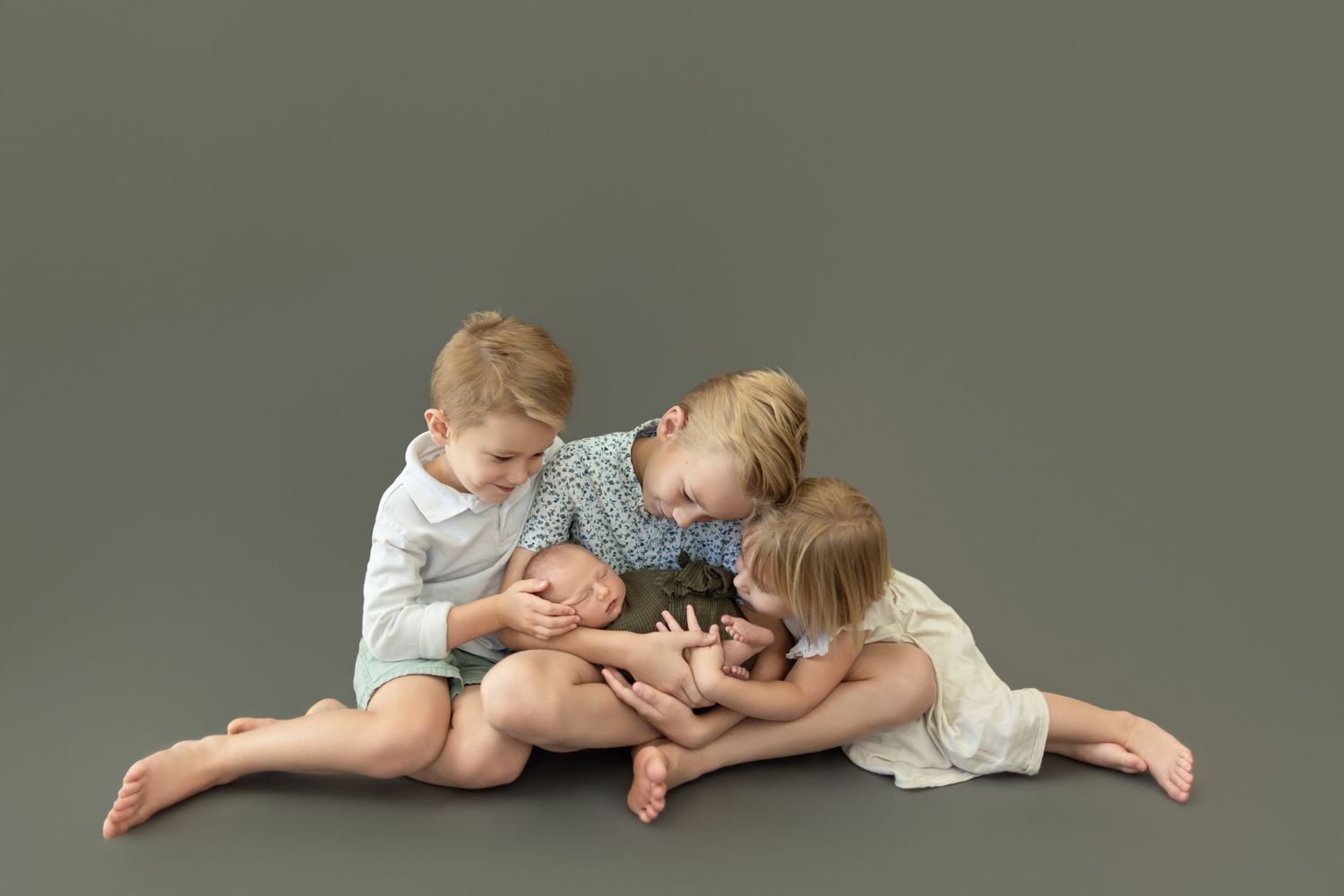Children in white clothing lie playfully on the floor during a photo shoot. Photos by Tampa Photographer DigitalMyst Photography