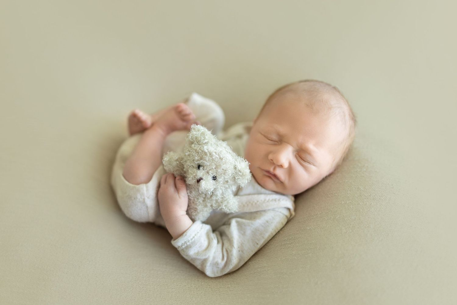 Sleeping newborn in white clothing rests peacefully during a professional photo session. Photos by Tampa Photographer DigitalMyst Photograph