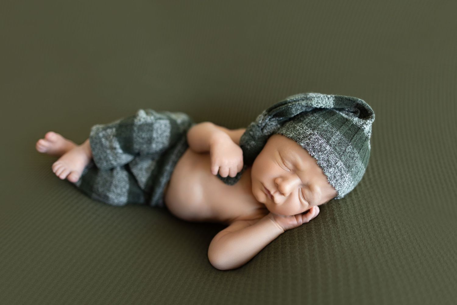 Newborn baby sleeps peacefully in gray knit outfit on textured background. Photos by Tampa Photographer DigitalMyst Photography