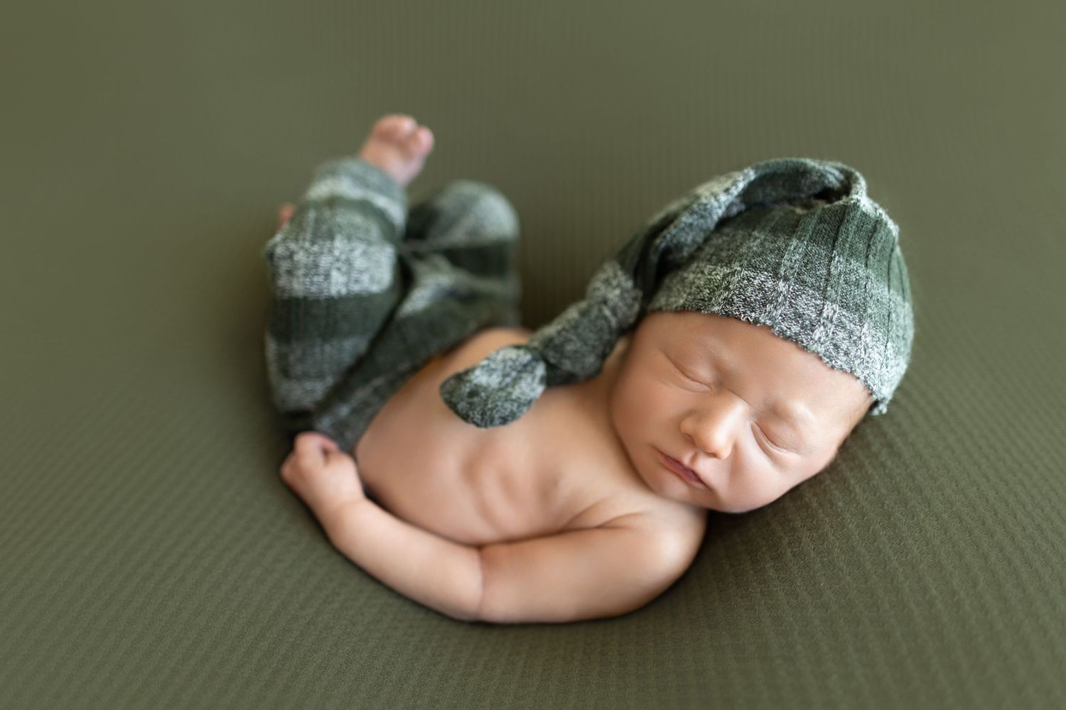 Sleeping newborn wrapped in gray knit fabric on dark backdrop. Photos by Tampa Photographer DigitalMyst Photography