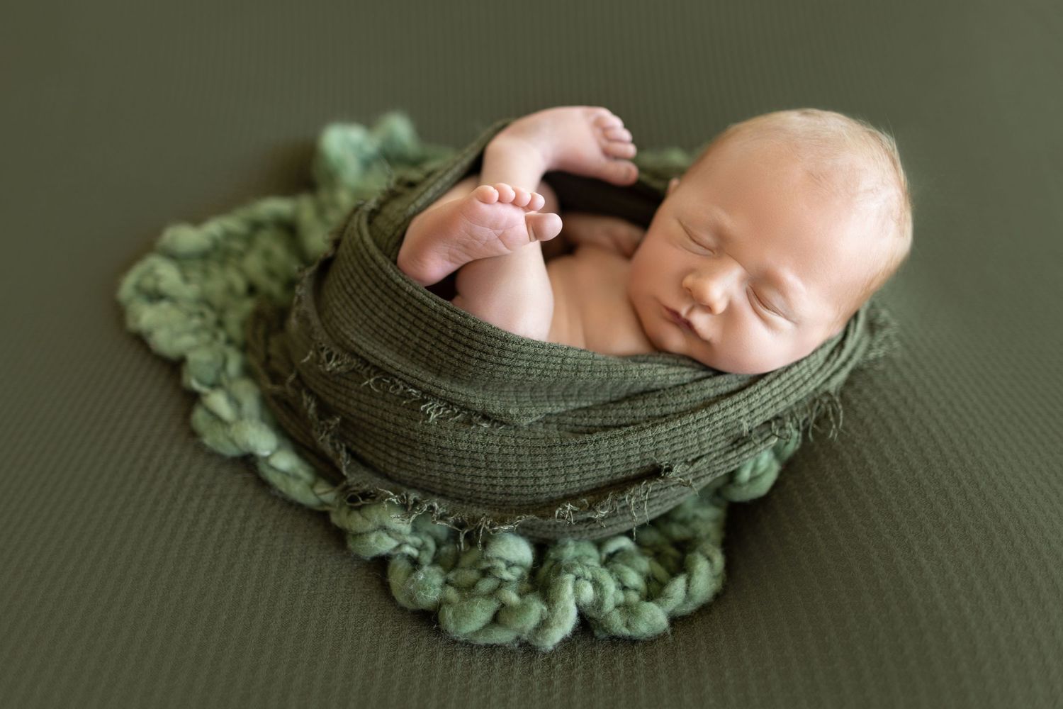 Peaceful newborn sleeps nestled in green wreath and knit wrap. Photos by Tampa Photographer DigitalMyst Photography