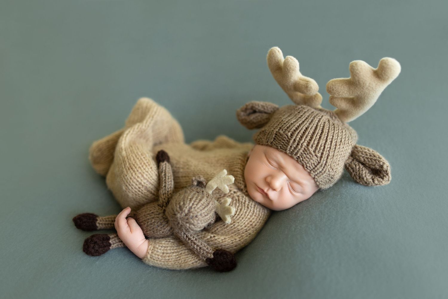 Sleeping newborn wearing knitted moose outfit on green background. Photos by Tampa Photographer DigitalMyst Photography