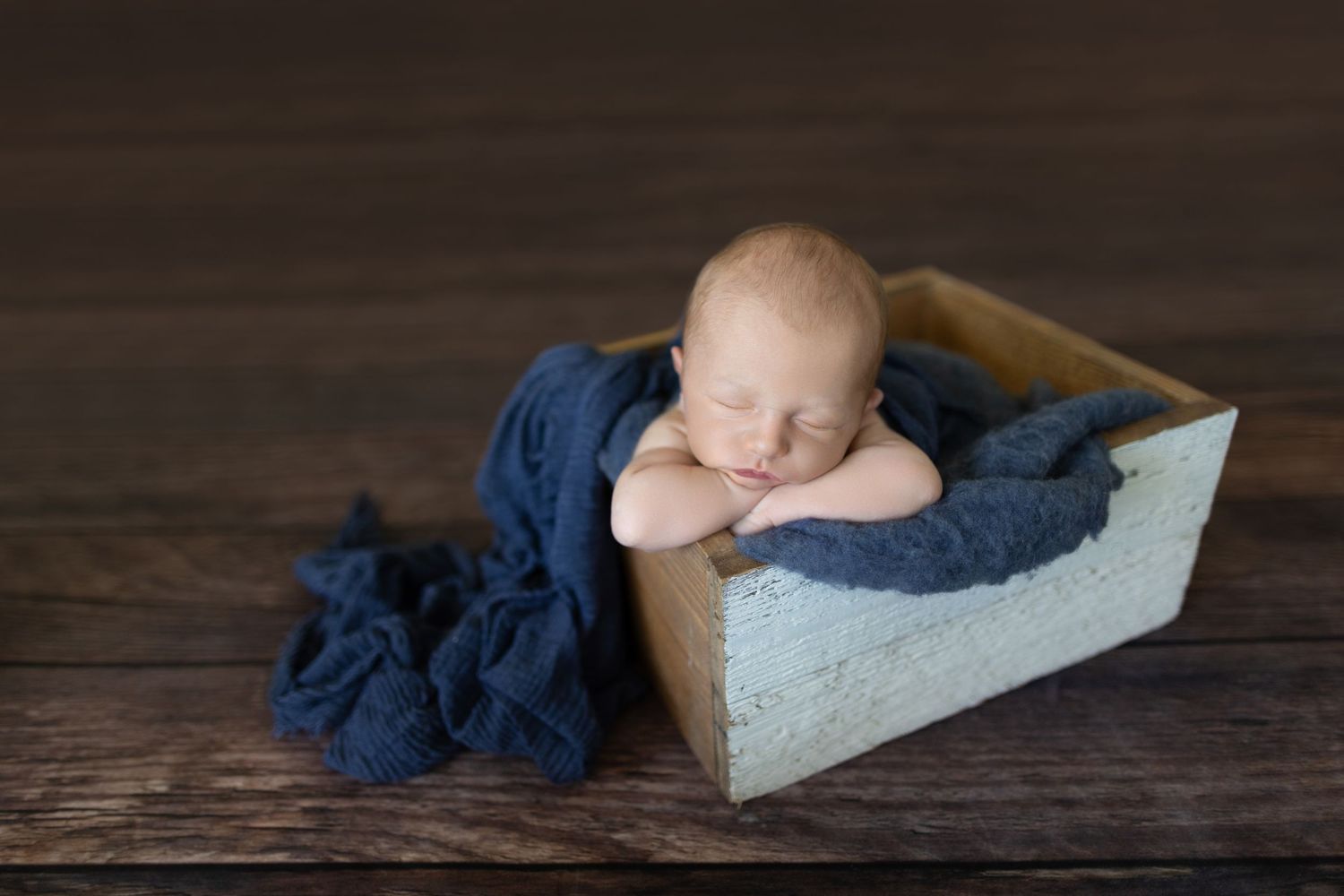 Newborn baby sleeping in rustic wooden box with navy blue fabric. Photos by Tampa Photographer DigitalMyst Photography