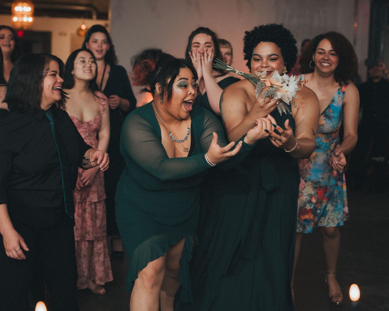 A joyful group of friends laughing and dancing together at a party in evening attire.