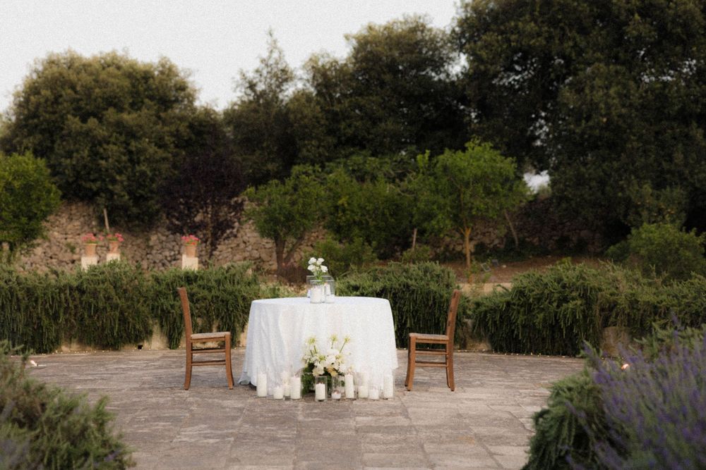 A rustic outdoor wedding ceremony setup with wooden chairs and floral arrangements in a natural garden setting.