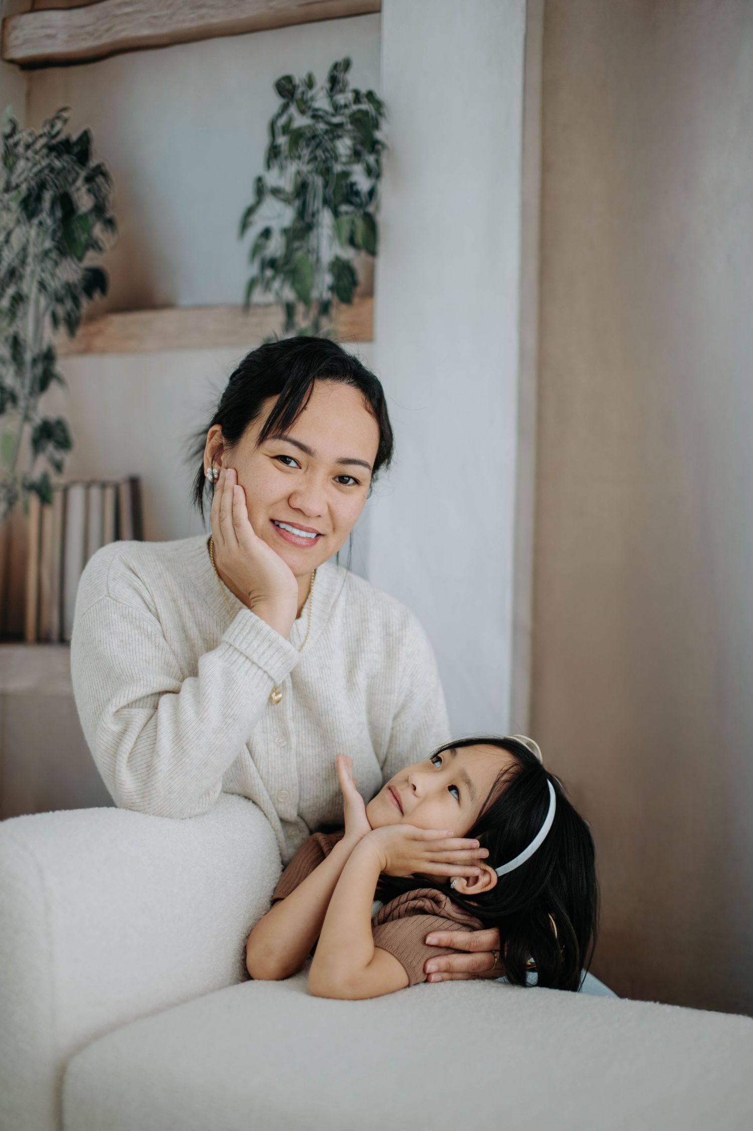 Mother and child share tender moments together while relaxing on white bedding.