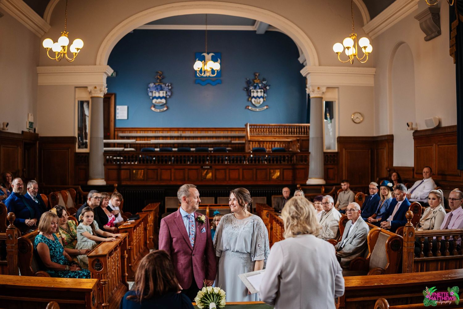Southport Town Hall ceremony in a traditional interior with elegant decor and wall-mounted sconces illuminating the space.