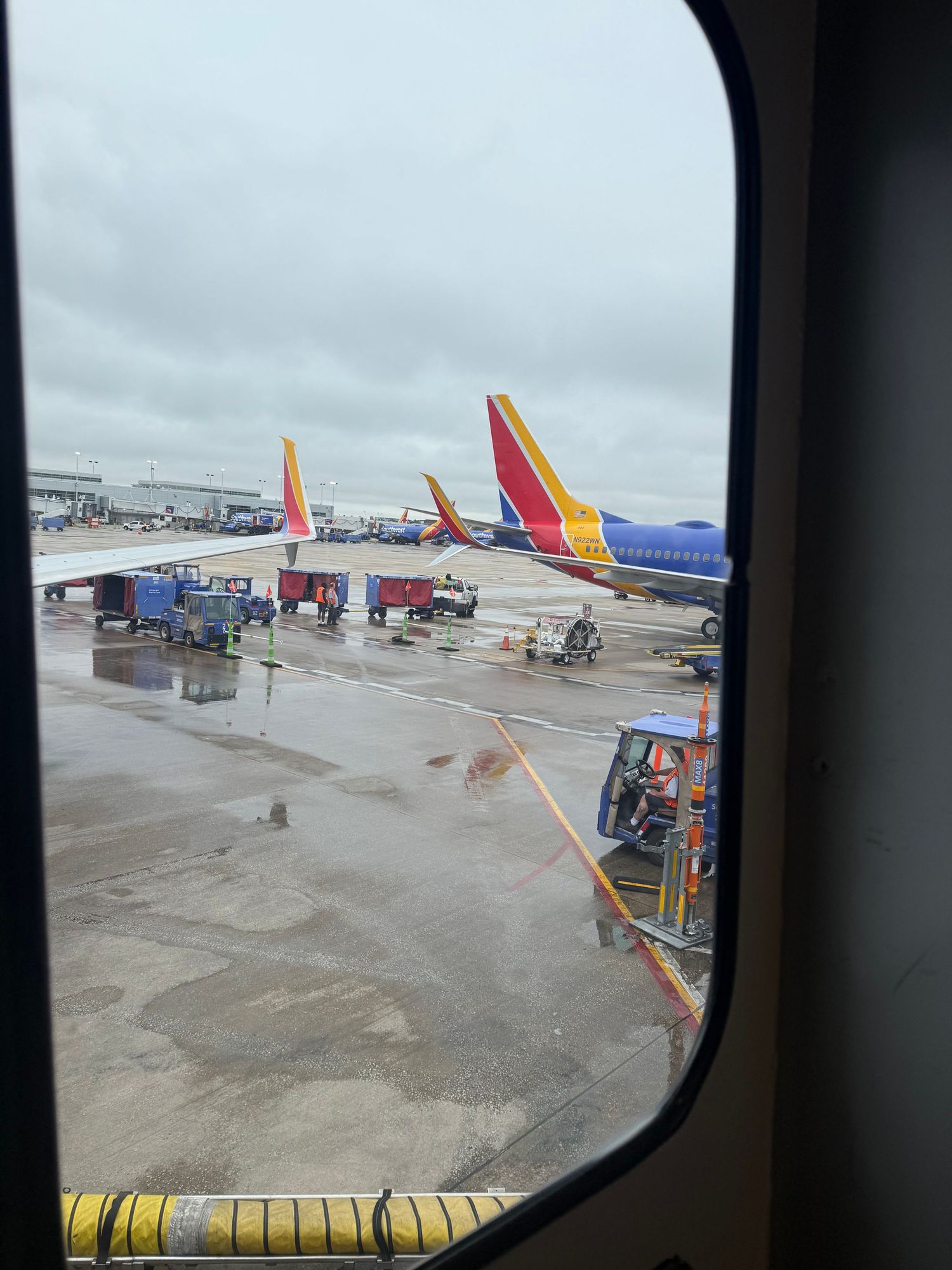 Southwest Airlines planes parked at airport gates visible through airplane window on cloudy day.