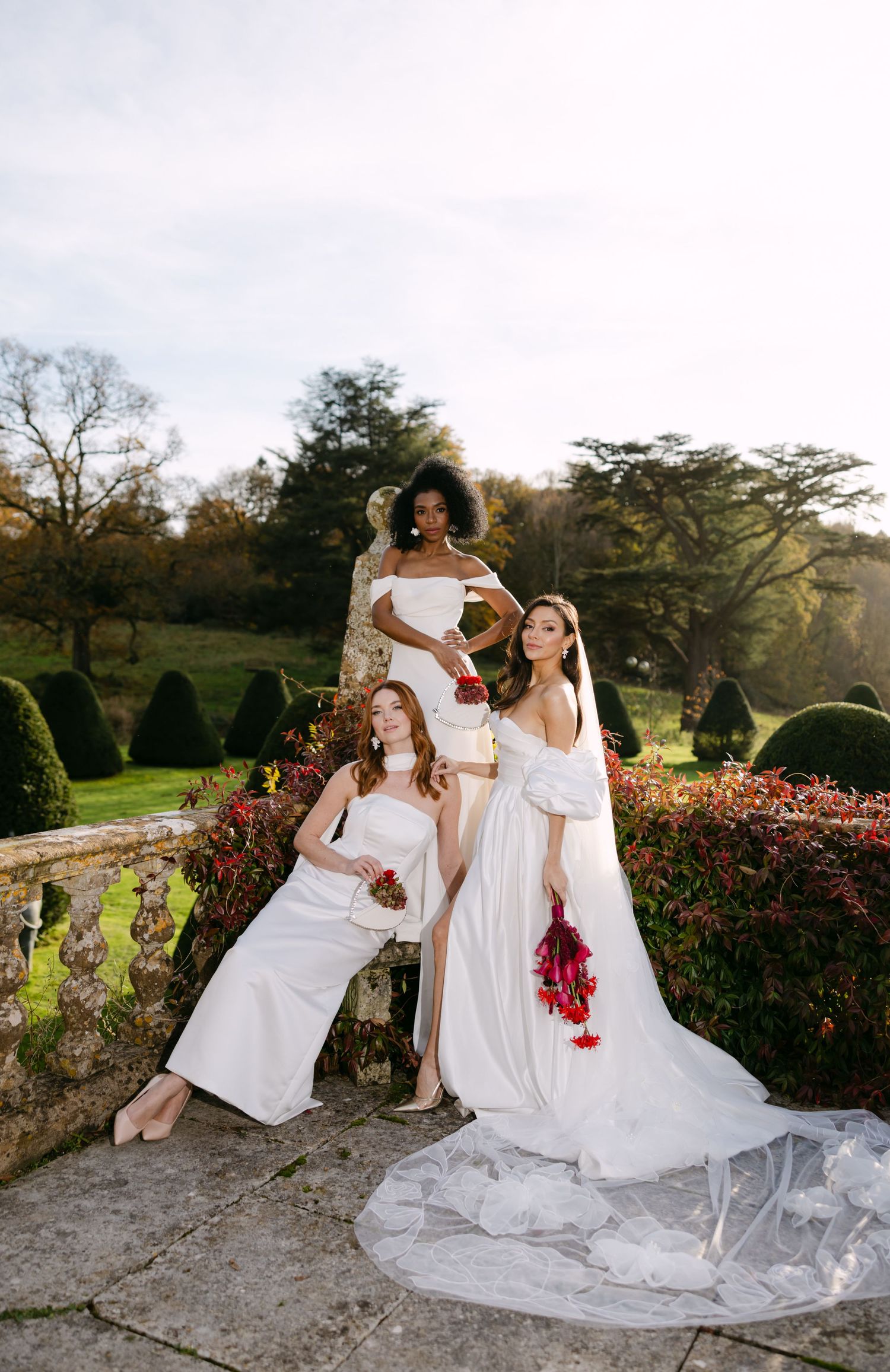 Group in white dresses posing together on stone steps in a garden setting.