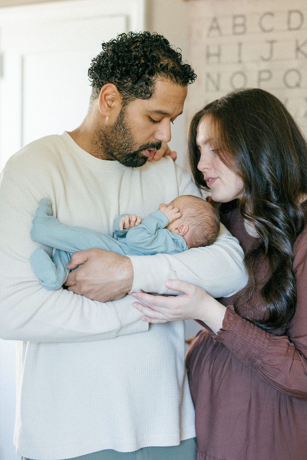 A series of tender moments between a couple holding their newborn baby in a naturally lit room.