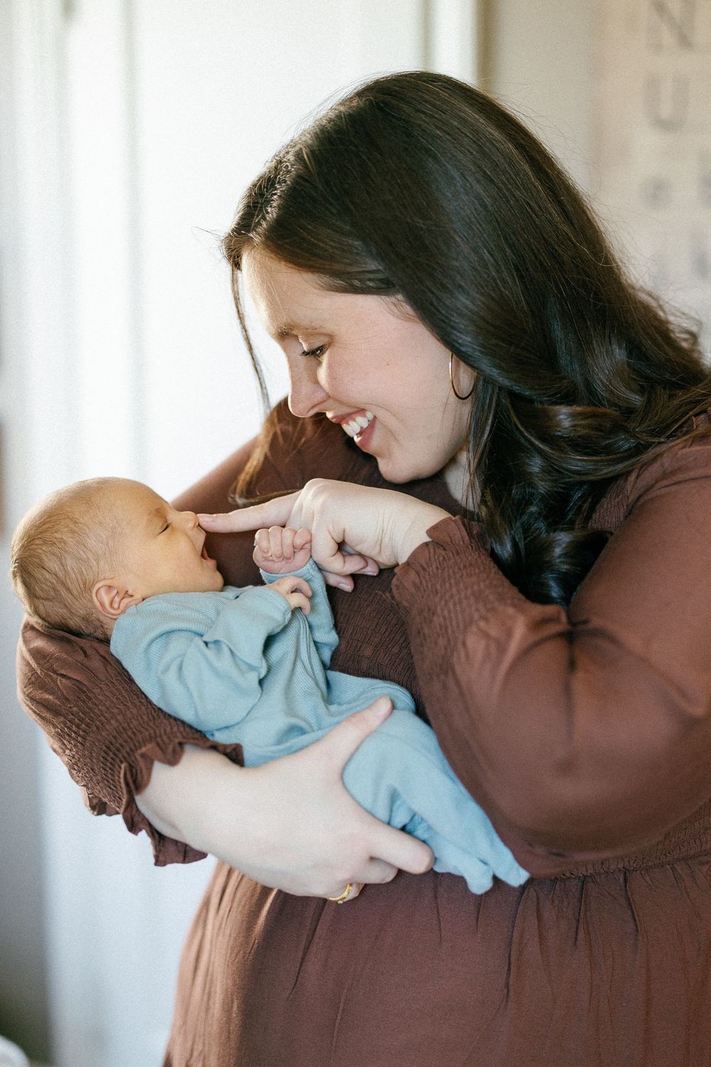 Woman in brown sweater holds and nuzzles baby in light blue outfit in series of tender moments.