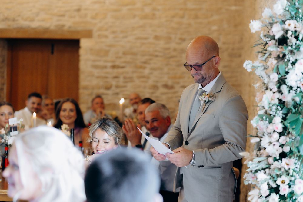 Wedding reception in a rustic stone venue with elegant white floral arch decorations.