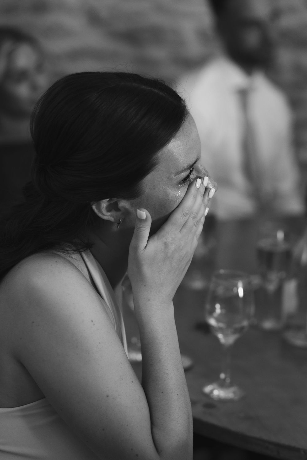 A series of black and white photos showing someone covering their face with their hands while sitting at a table.