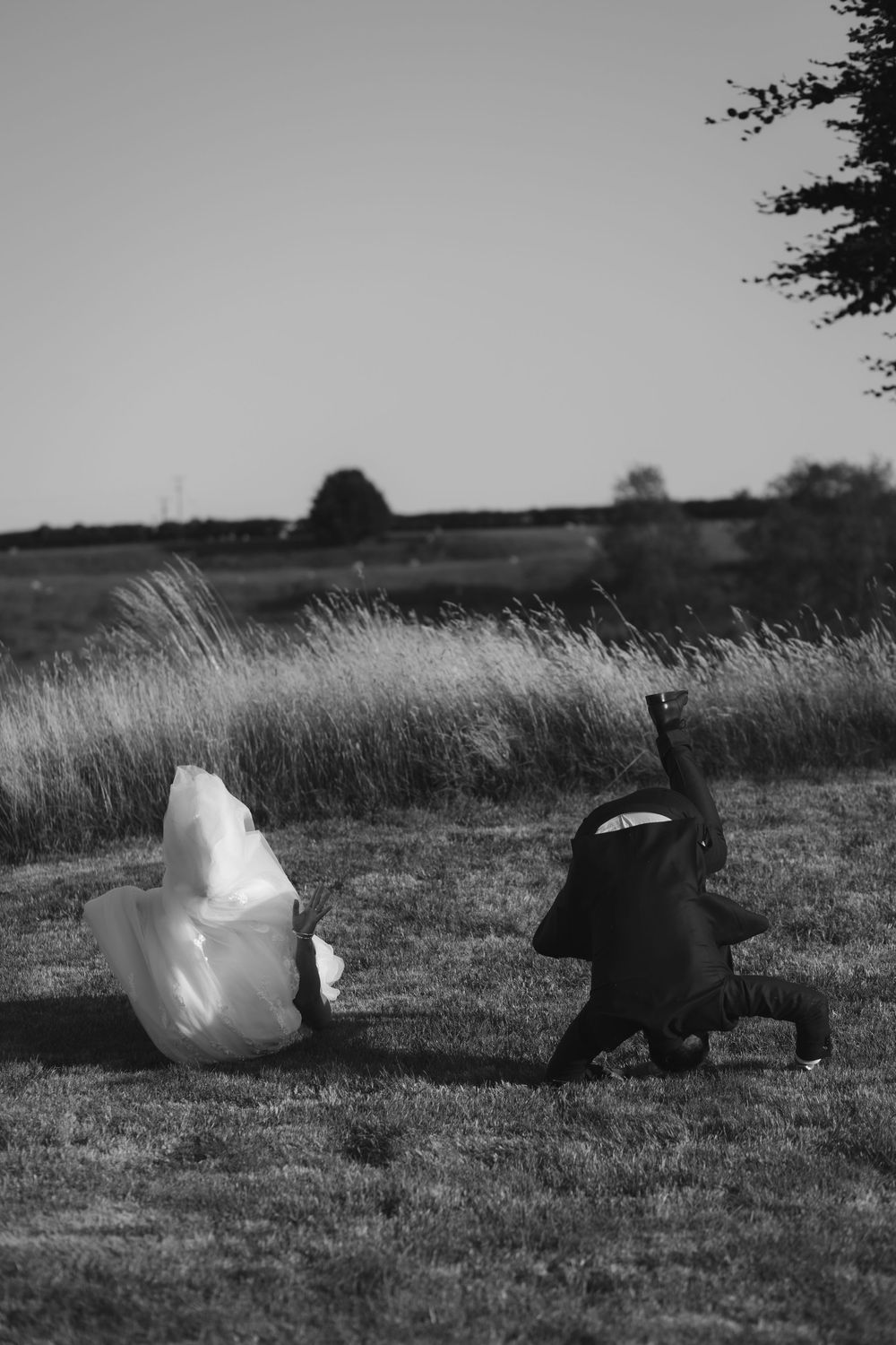 A dog playfully chases a floating plastic bag across a grassy field in black and white.